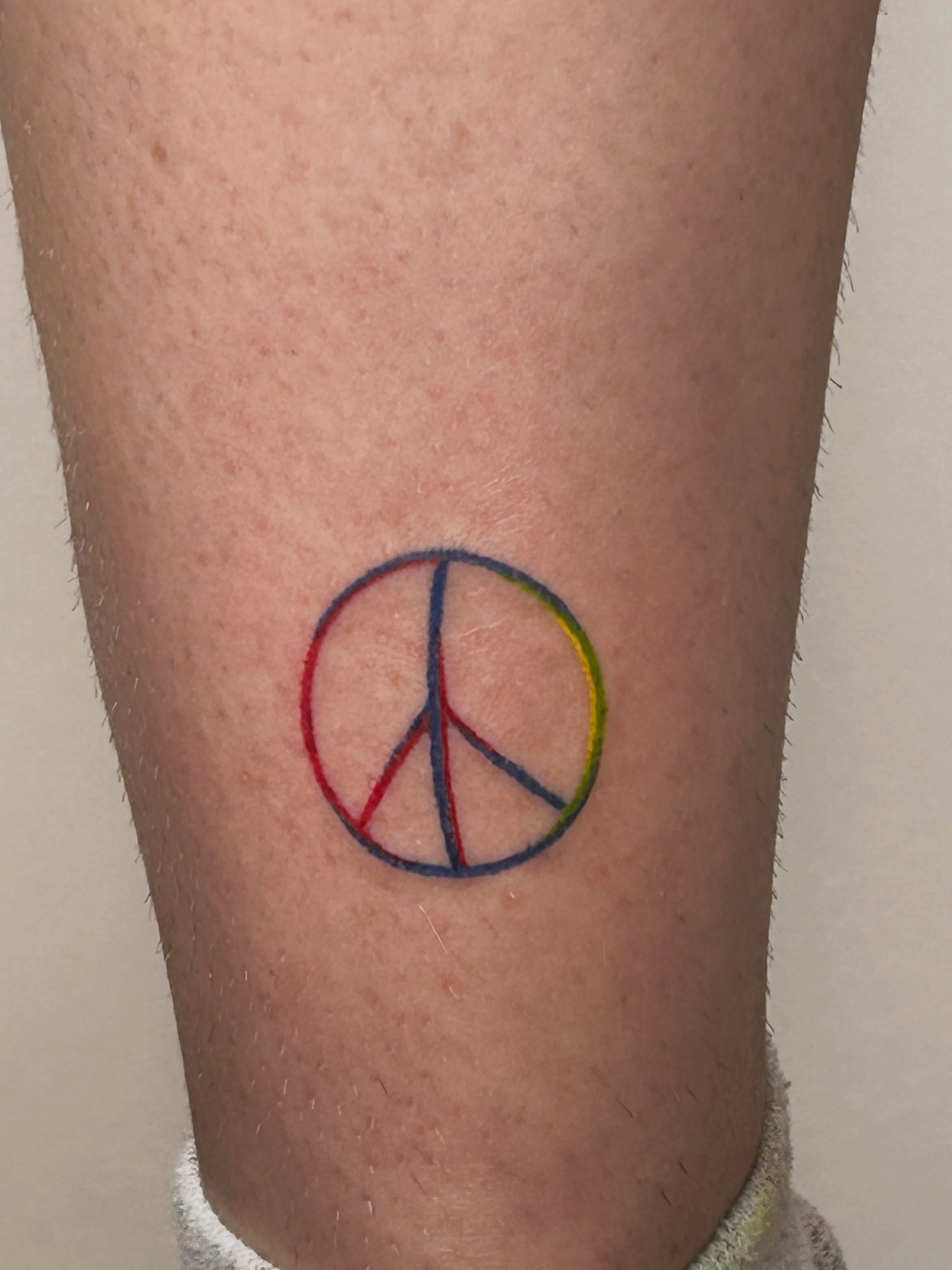 Peace symbol geometric tattoo on the forearm by Nicolette