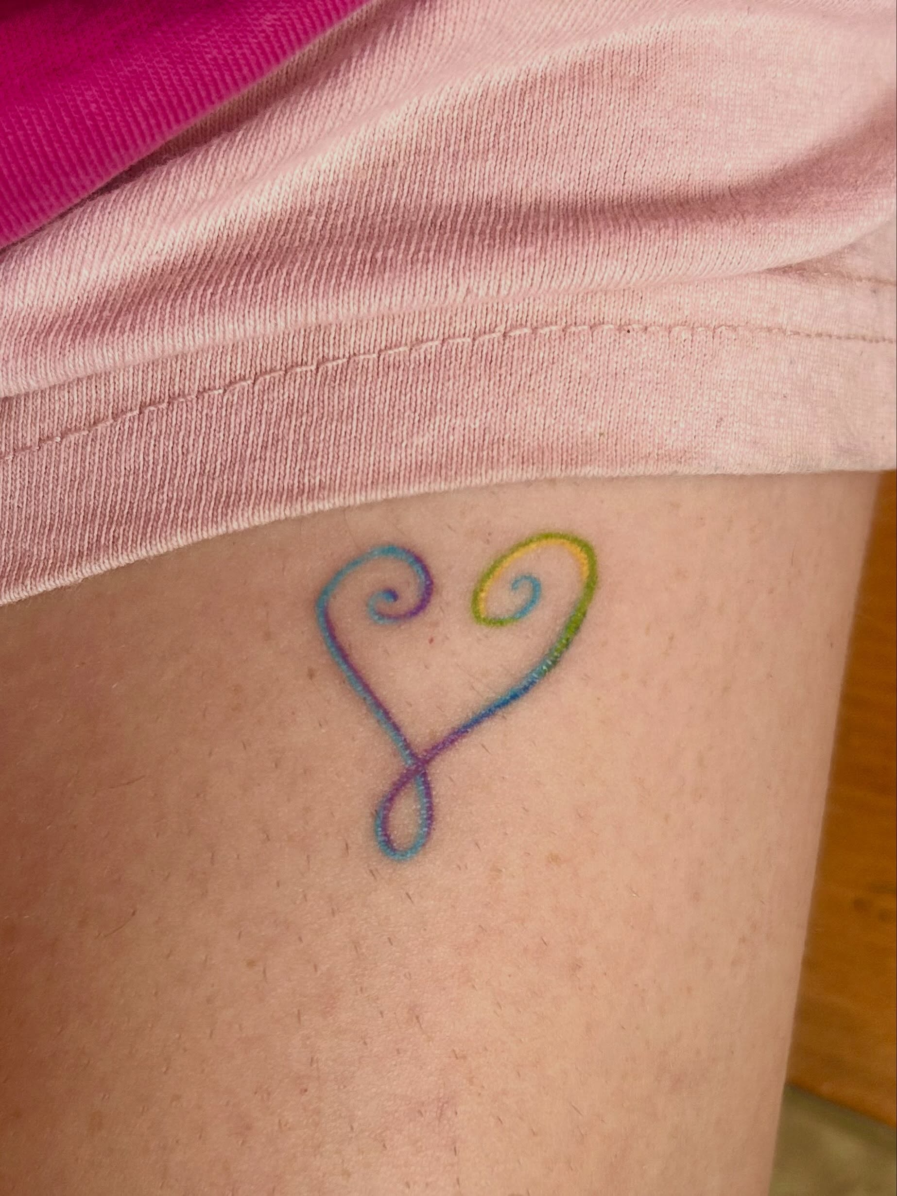 Heart fine line tattoo on the thigh by Nicolette