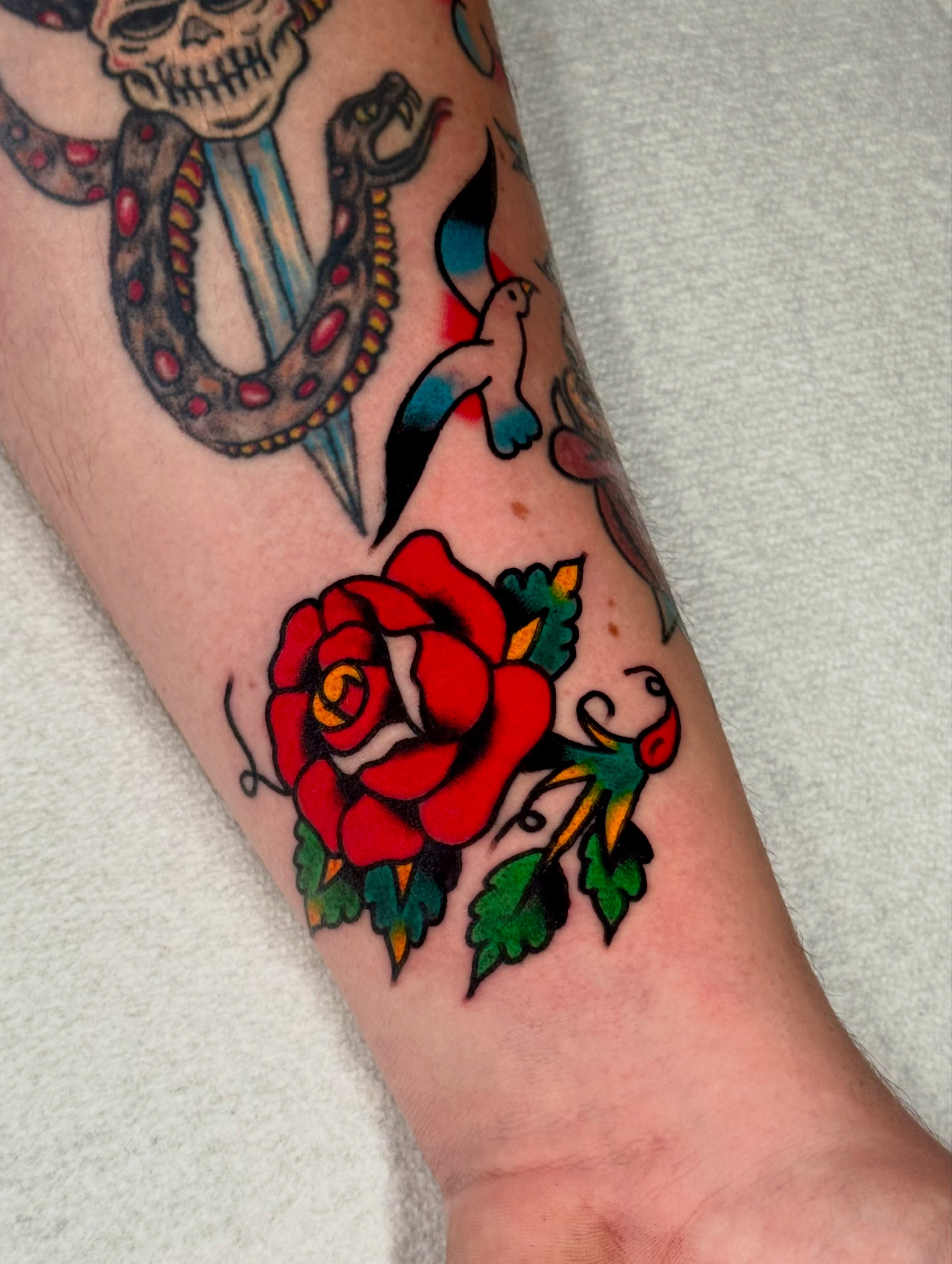 Red rose American traditional tattoo on the forearm by Joe Bear Tattooer