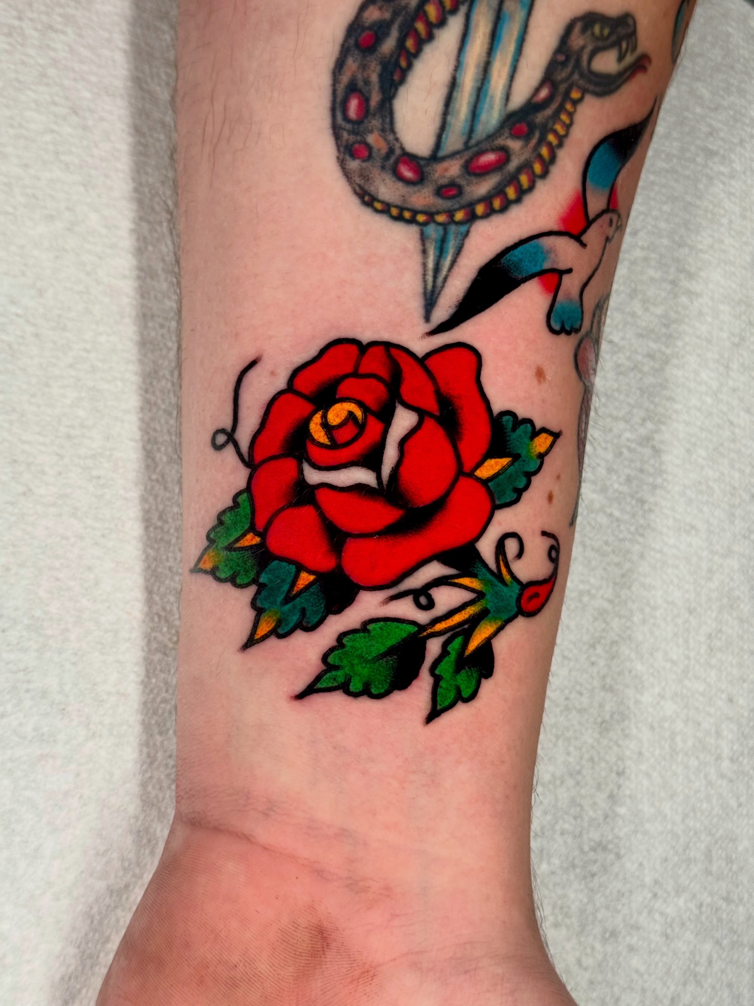 Red rose American traditional tattoo on the forearm by Joe Bear Tattooer