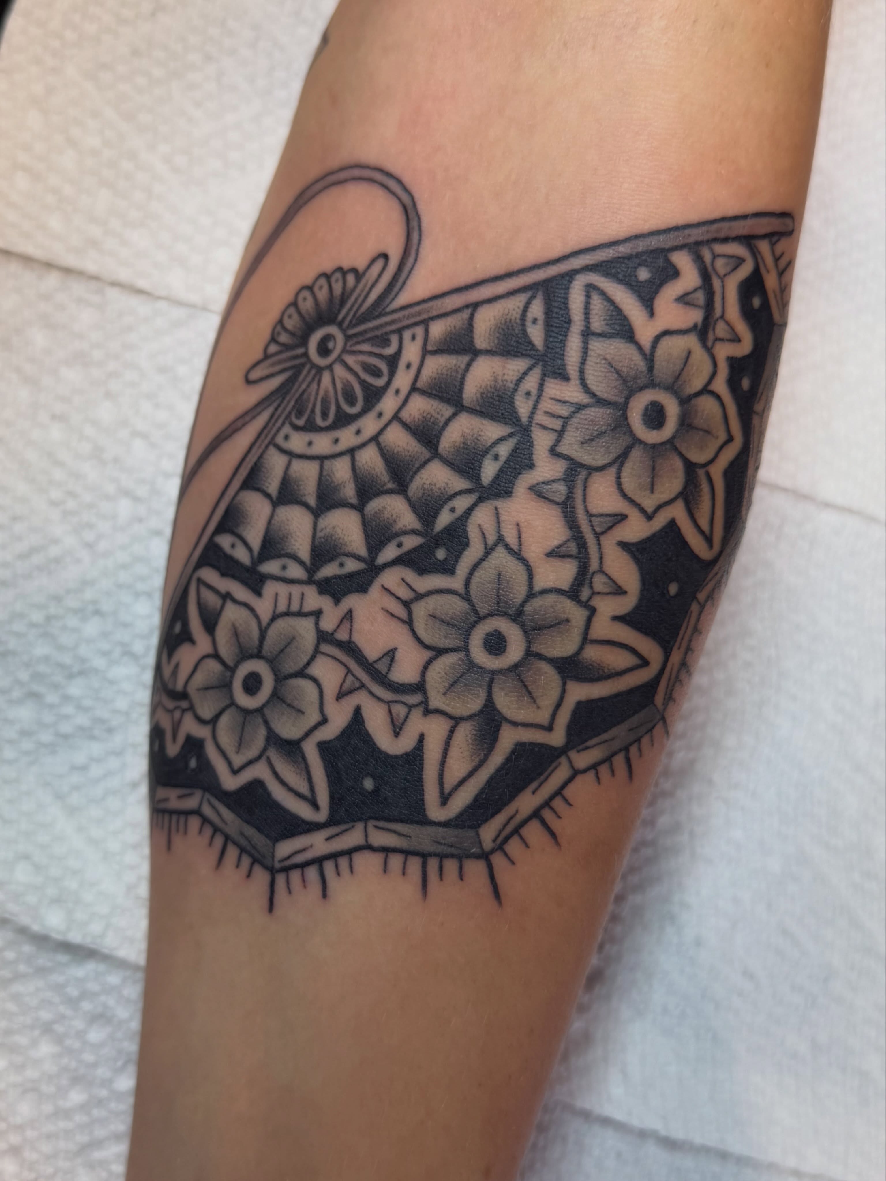 Lace pattern black and grey tattoo on the forearm by Evan Voelker