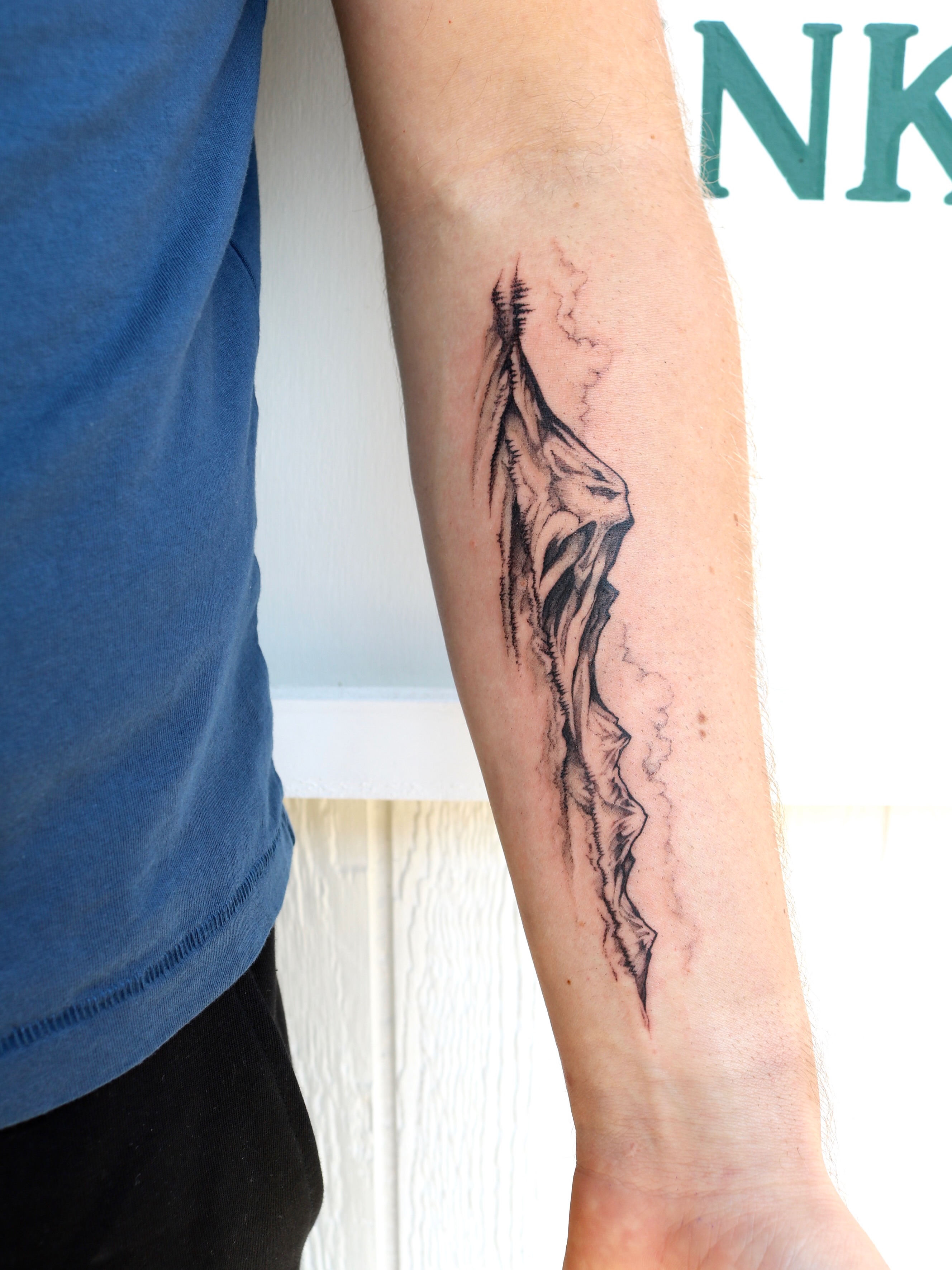 Cliff black and grey tattoo on the forearm by Kingtide Ink