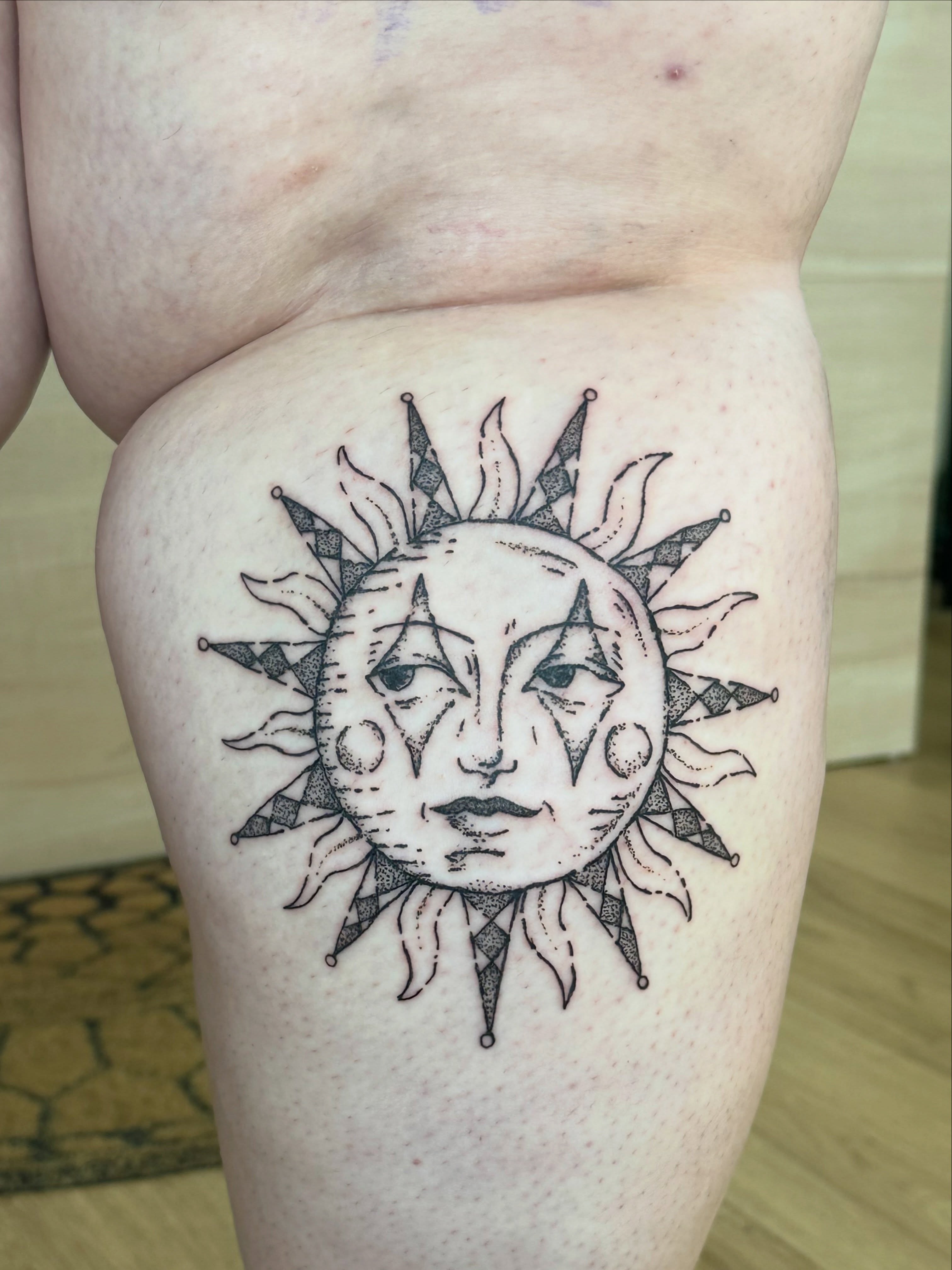 Sun face black and grey tattoo on the thigh by Fleur ๐ฅ