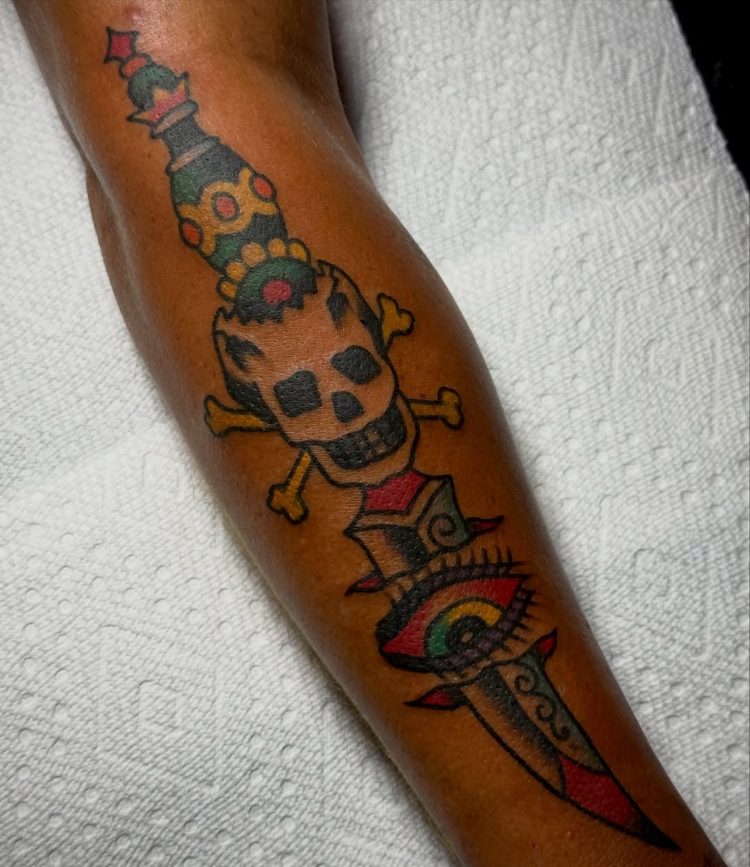 Skull and crossbones with dagger American traditional tattoo on the forearm by Chuck Derek Whitaker