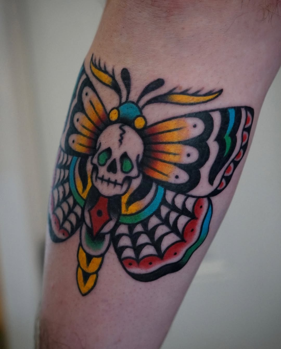Skull and butterfly American traditional tattoo on the forearm by Emily Devenz
