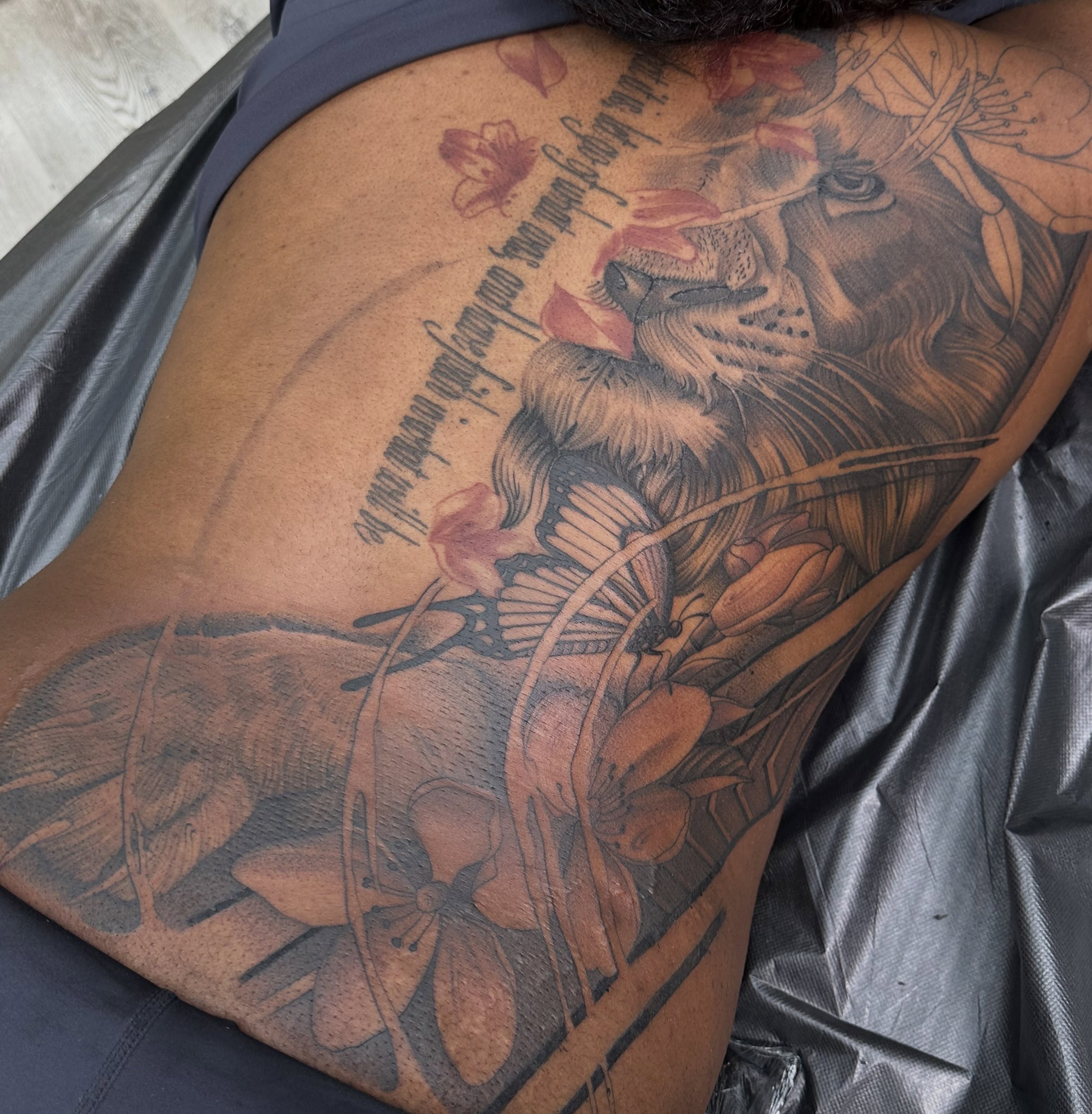 Lion and flowers realism tattoo on the thigh by San Diego Tattoo Artist