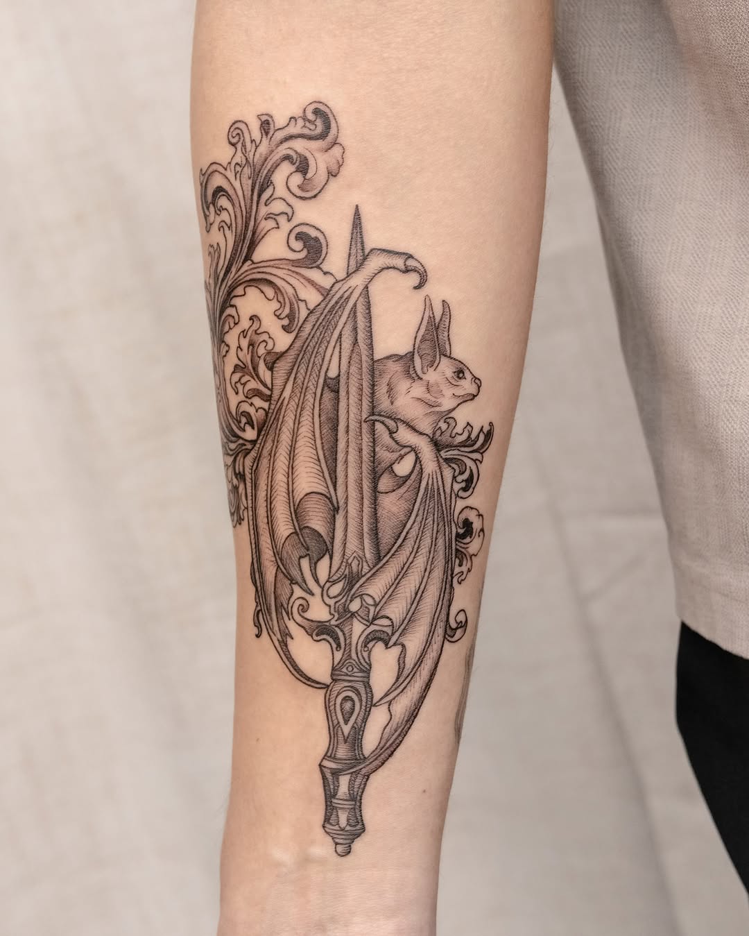 Bat and ornate dagger ornamental tattoo on the forearm by Koko