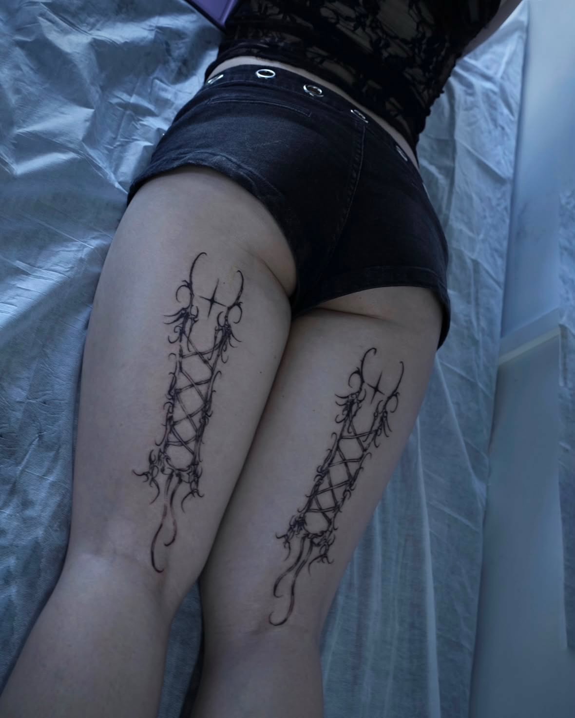 Corset lacing black and grey tattoo on the thigh by Gun