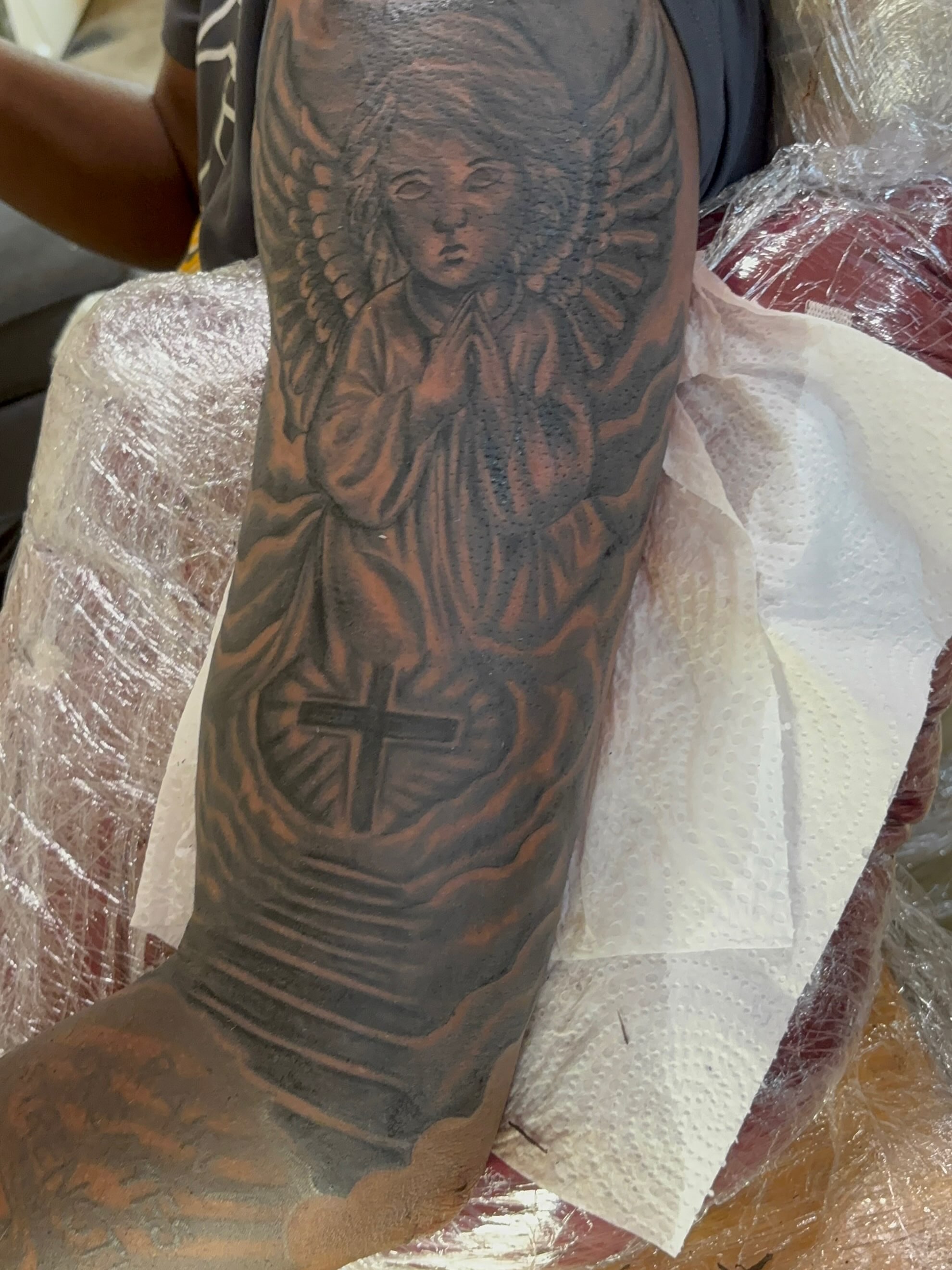 Angel with cross black and grey tattoo on the forearm by OwlWhoINKs