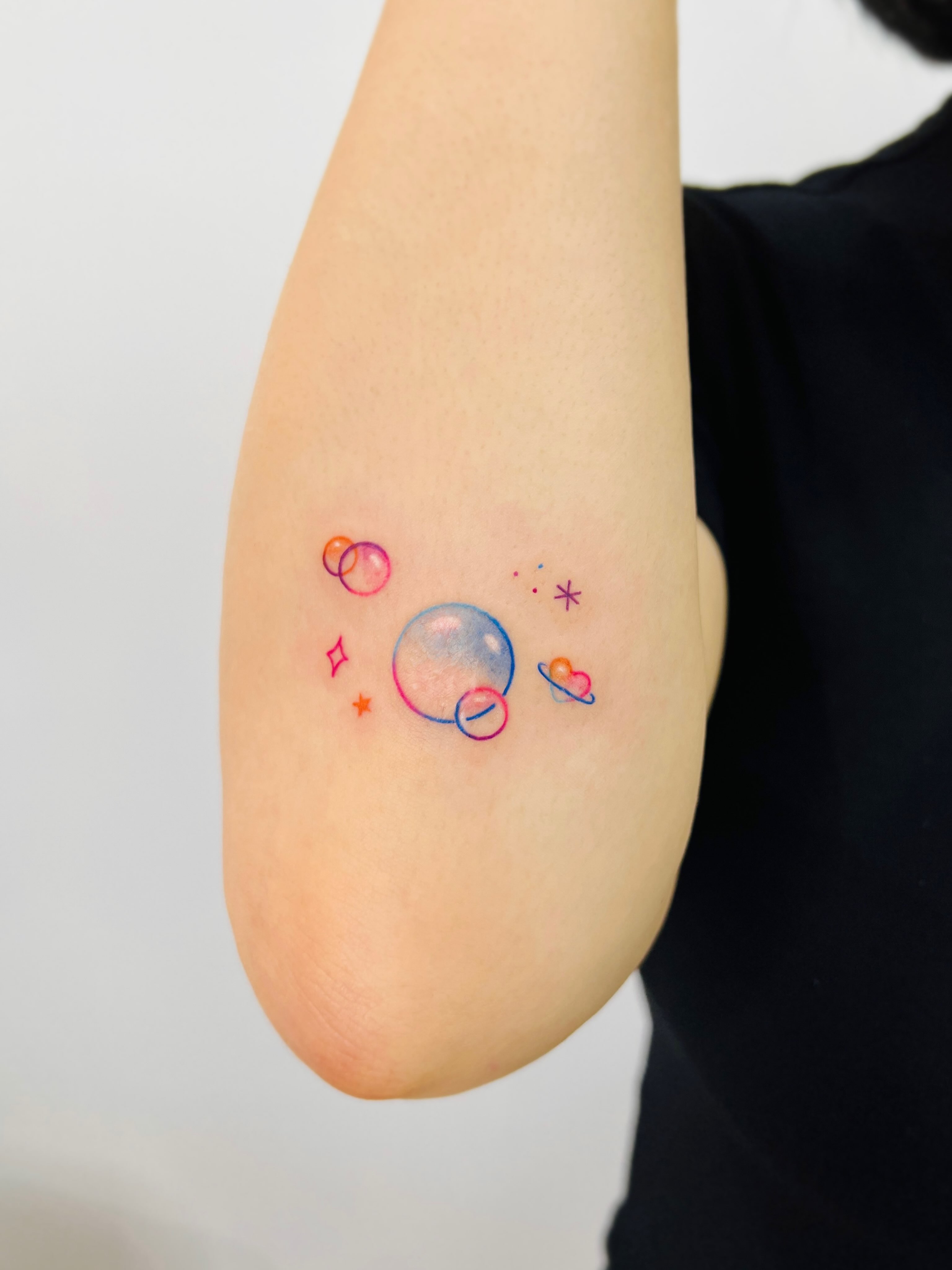 Space-themed watercolor tattoo on the forearm by Purinn