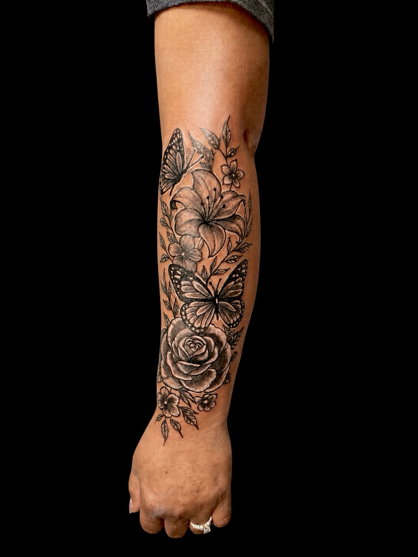 Floral and butterfly design black and grey tattoo on the forearm by Junior Sanchez Dfw