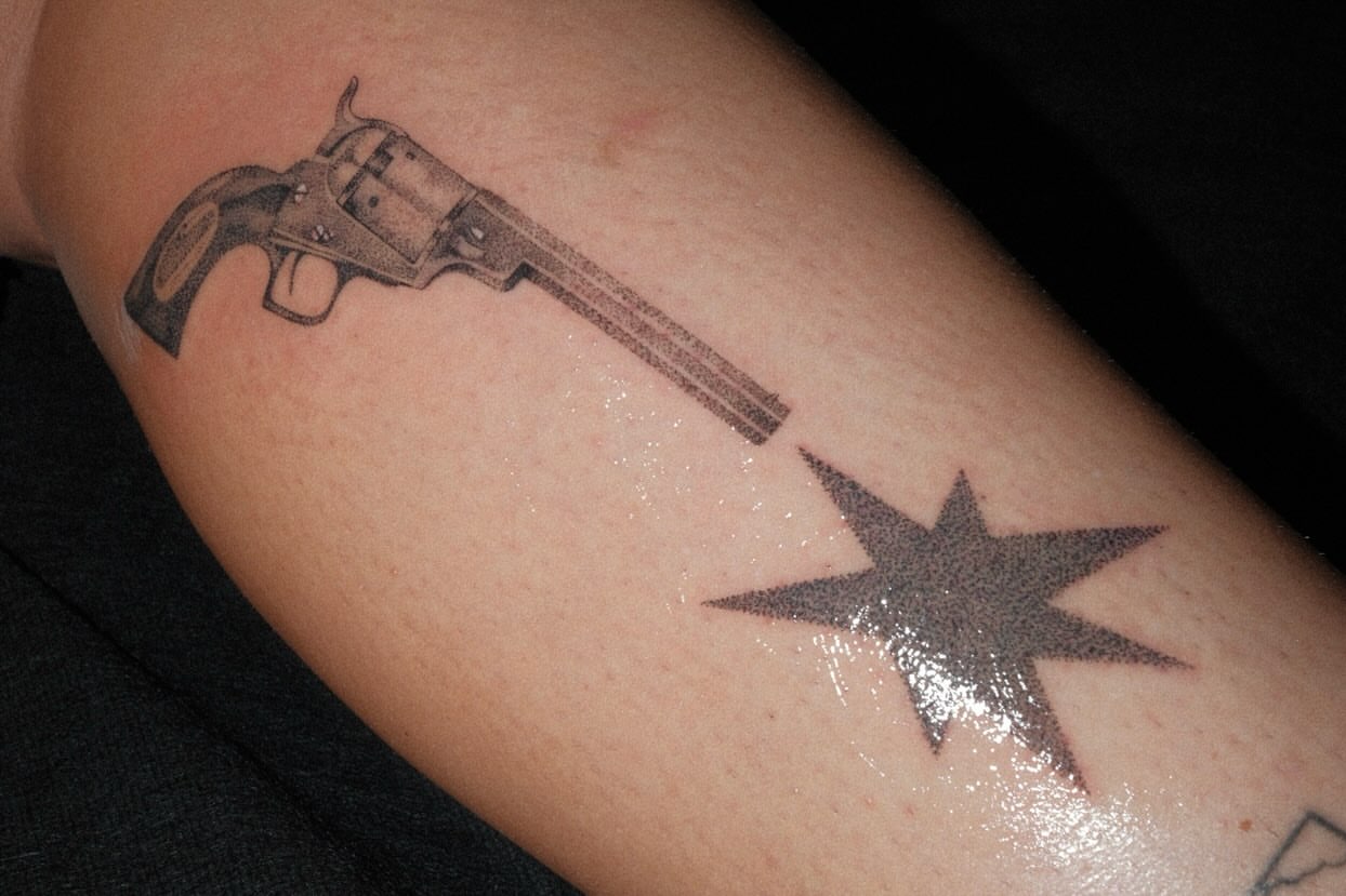 Revolver and star black and grey tattoo on the forearm by Thiên Hồ