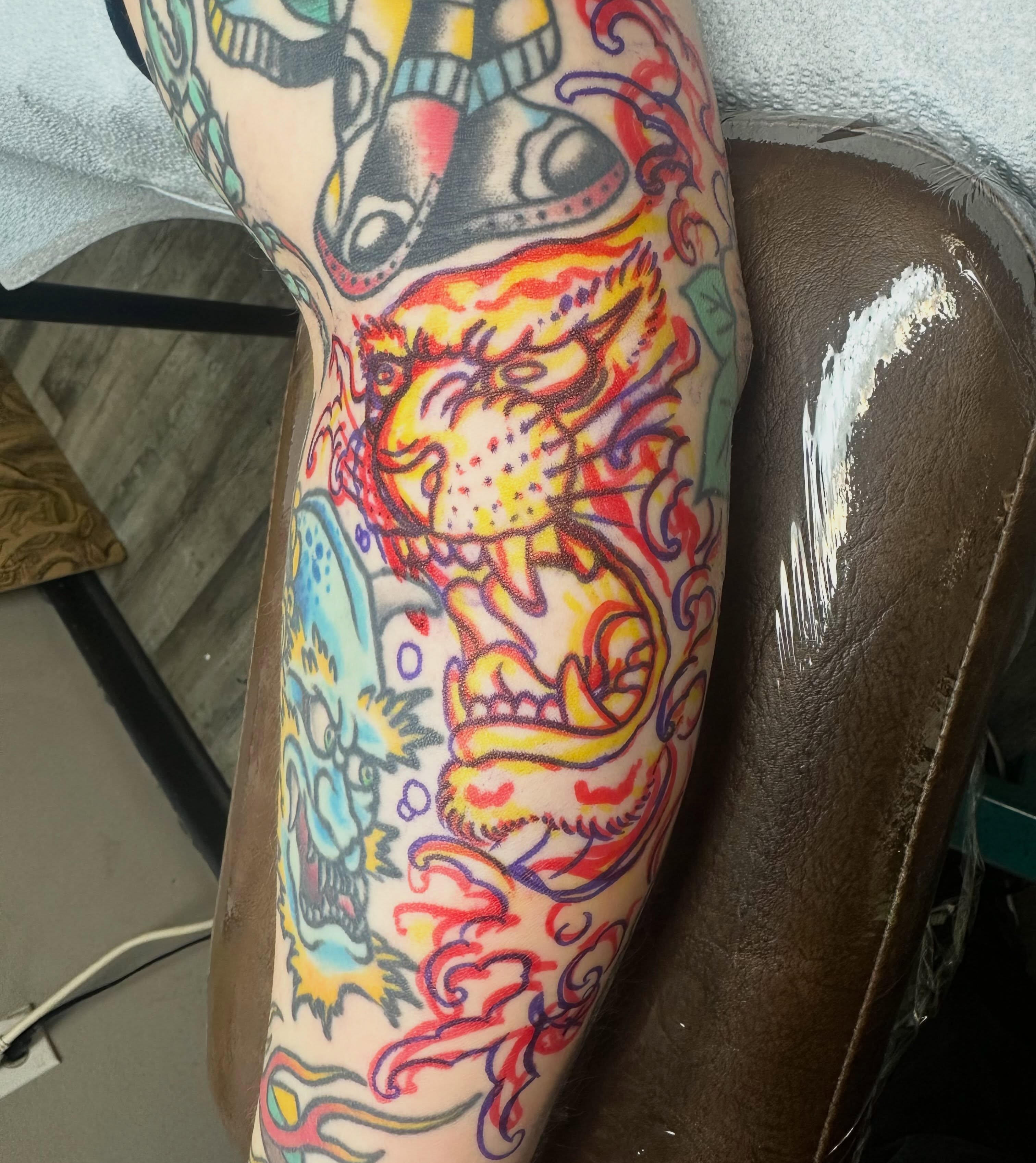 Lion and dragon American traditional tattoo on the forearm by Devin Spenny