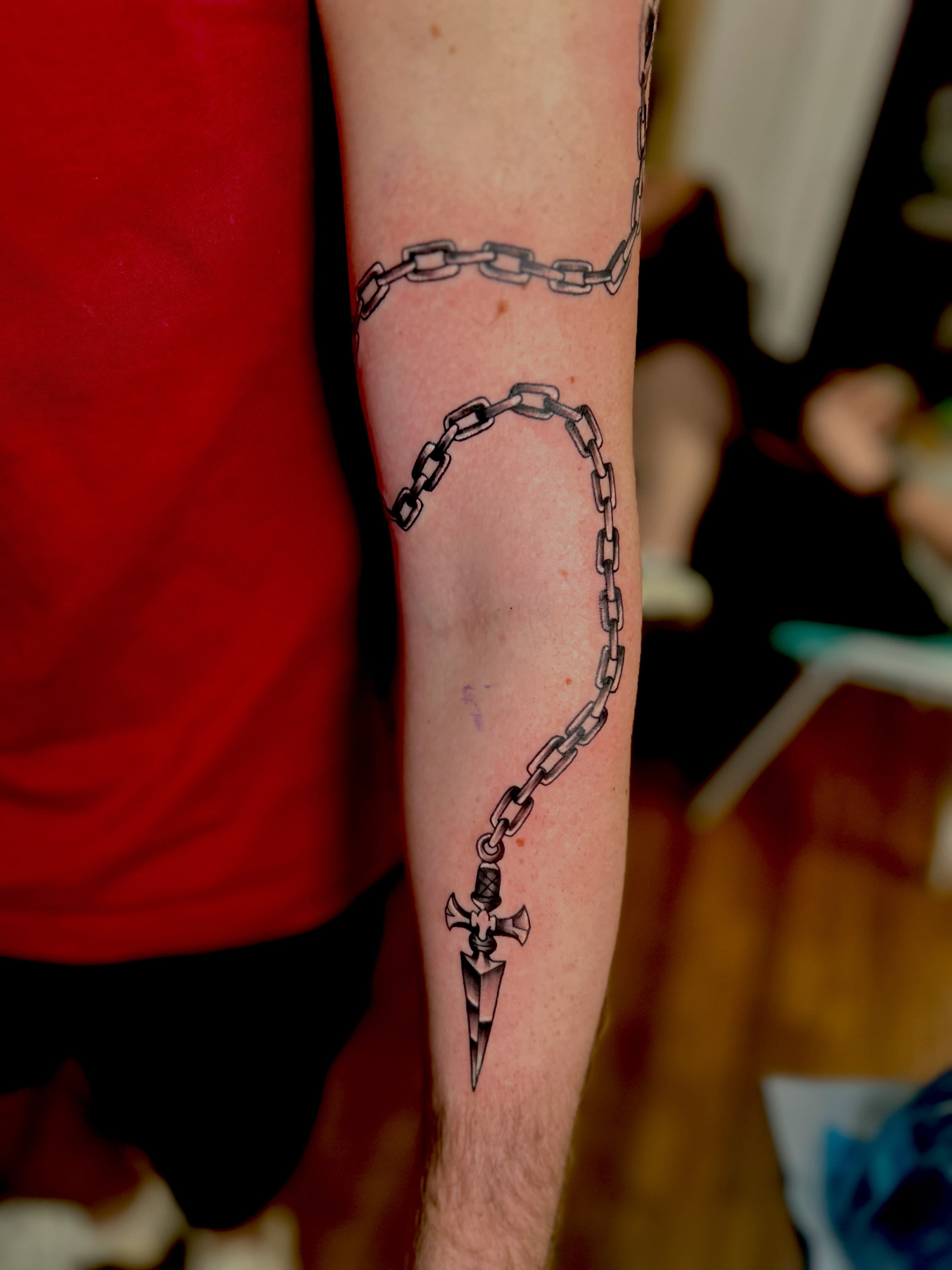 Chain and dagger black and grey tattoo on the forearm by Austin Young