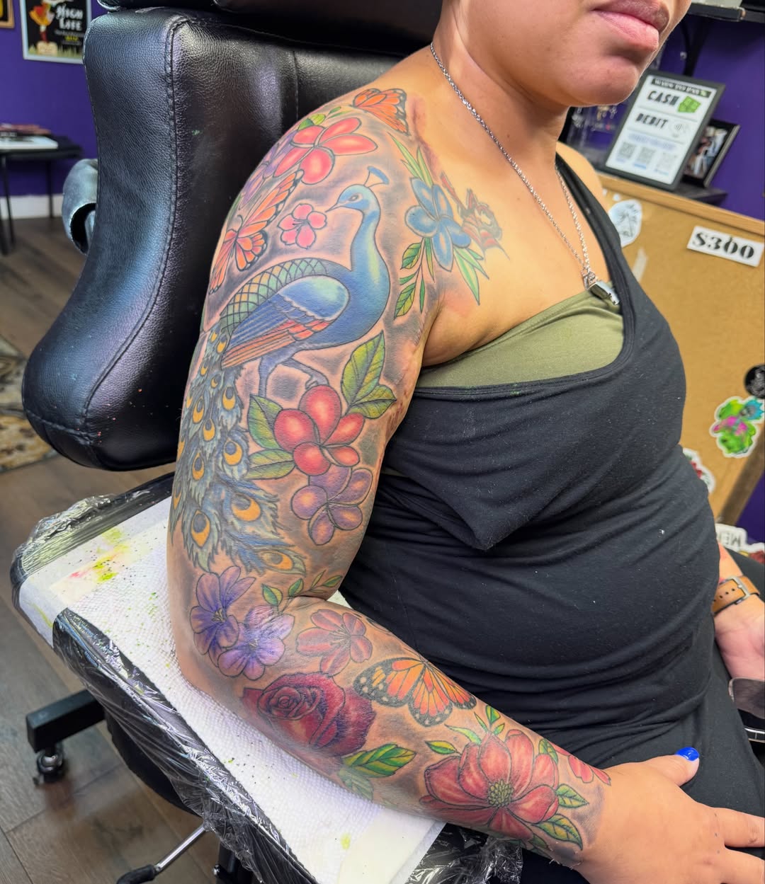 Peacock and floral new school tattoo on the upper arm by Christian Goines, Memphis, Tennessee
