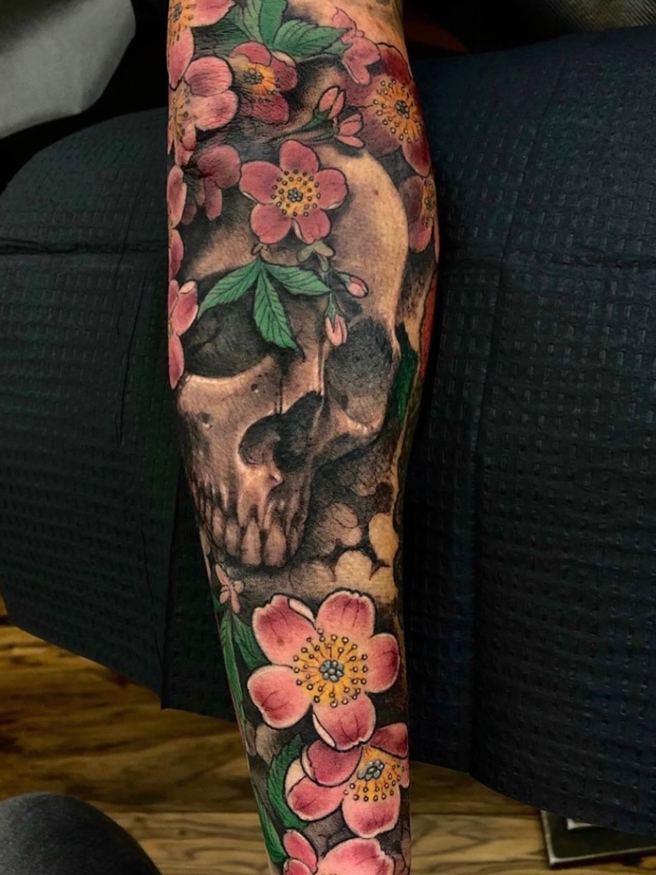 Skull and flowers realism tattoo on the forearm by jonhighland