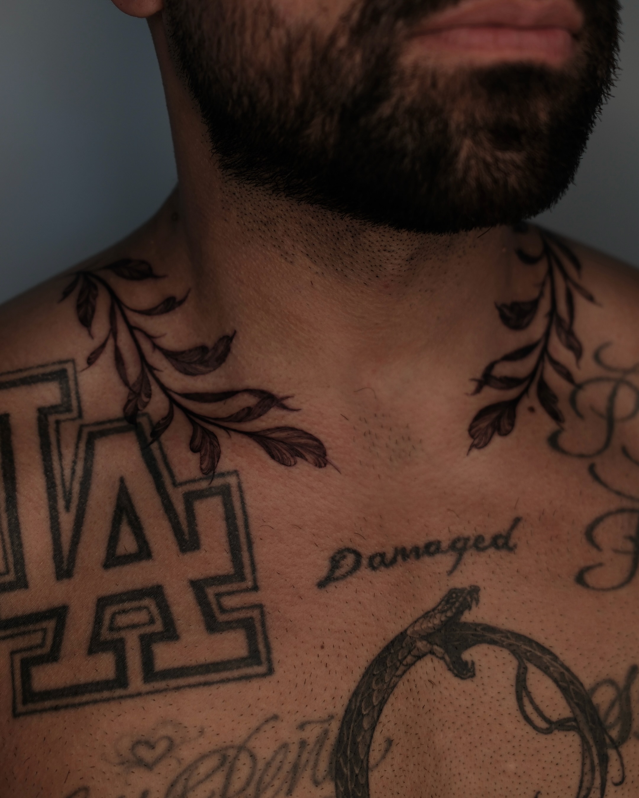 LA logo with floral elements black and grey tattoo on the chest by Sab