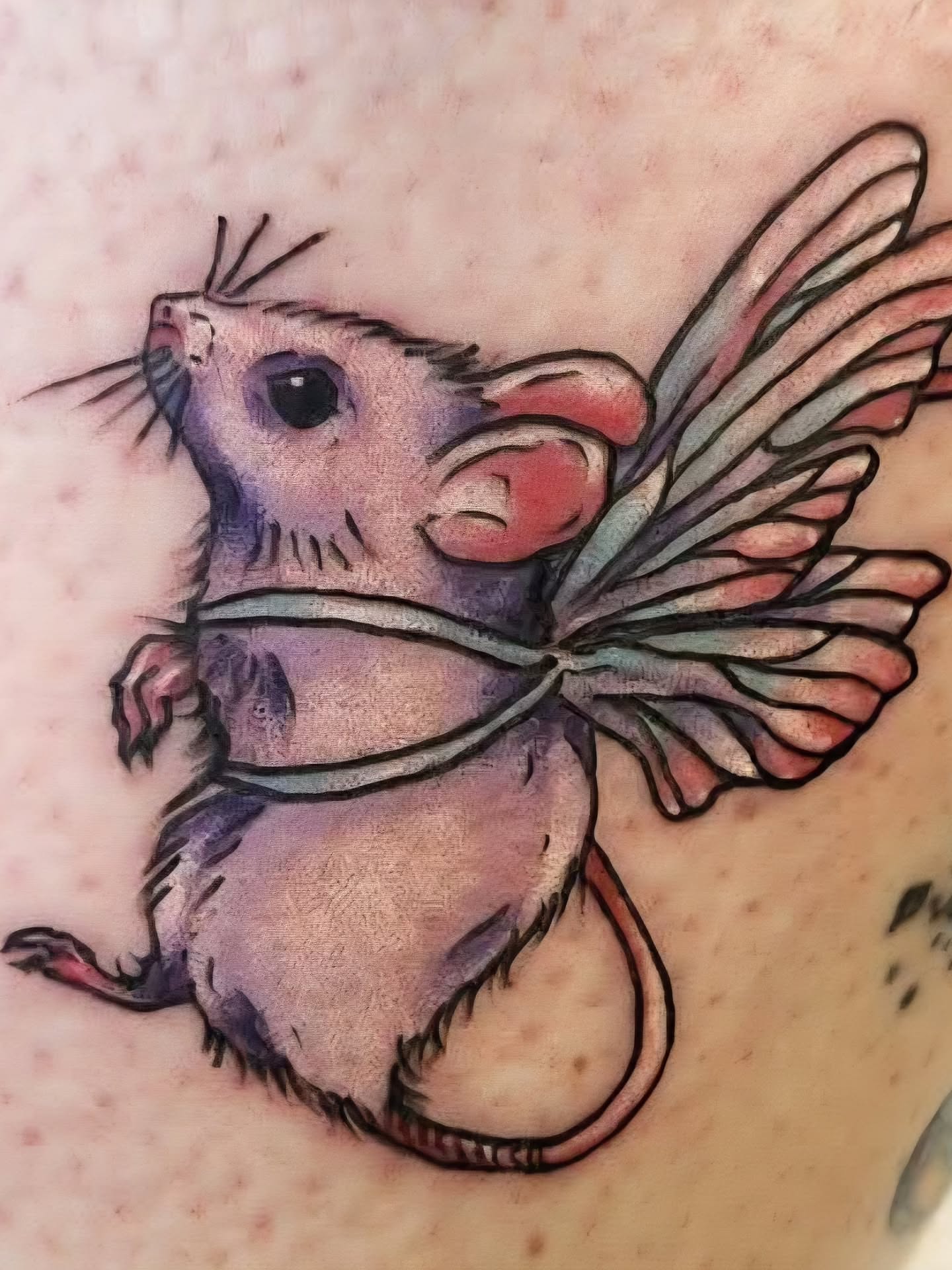 Mouse with wings watercolor tattoo on the upper arm by Heather