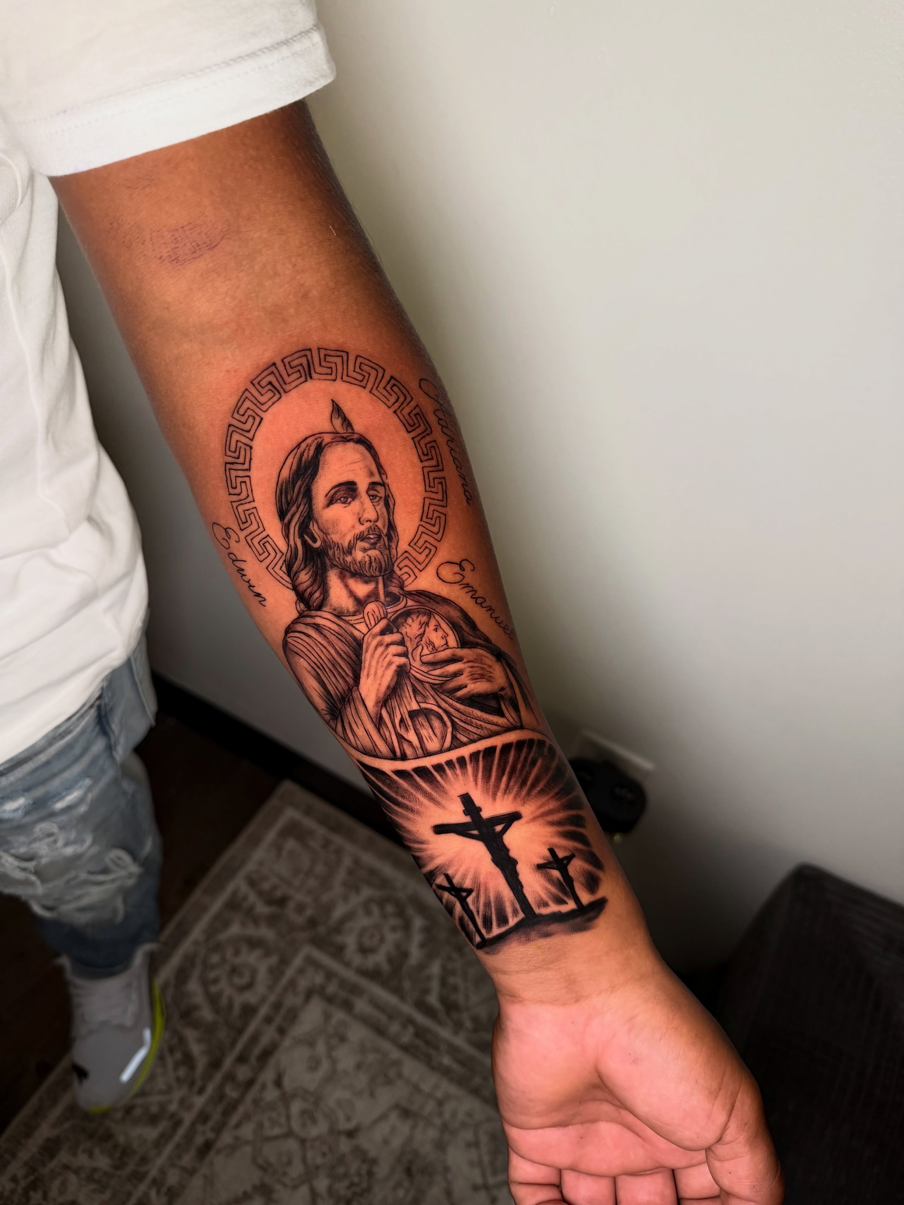 Religious figure holding baby black and grey tattoo on the forearm by Sebastian martinez, Memphis, Tennessee