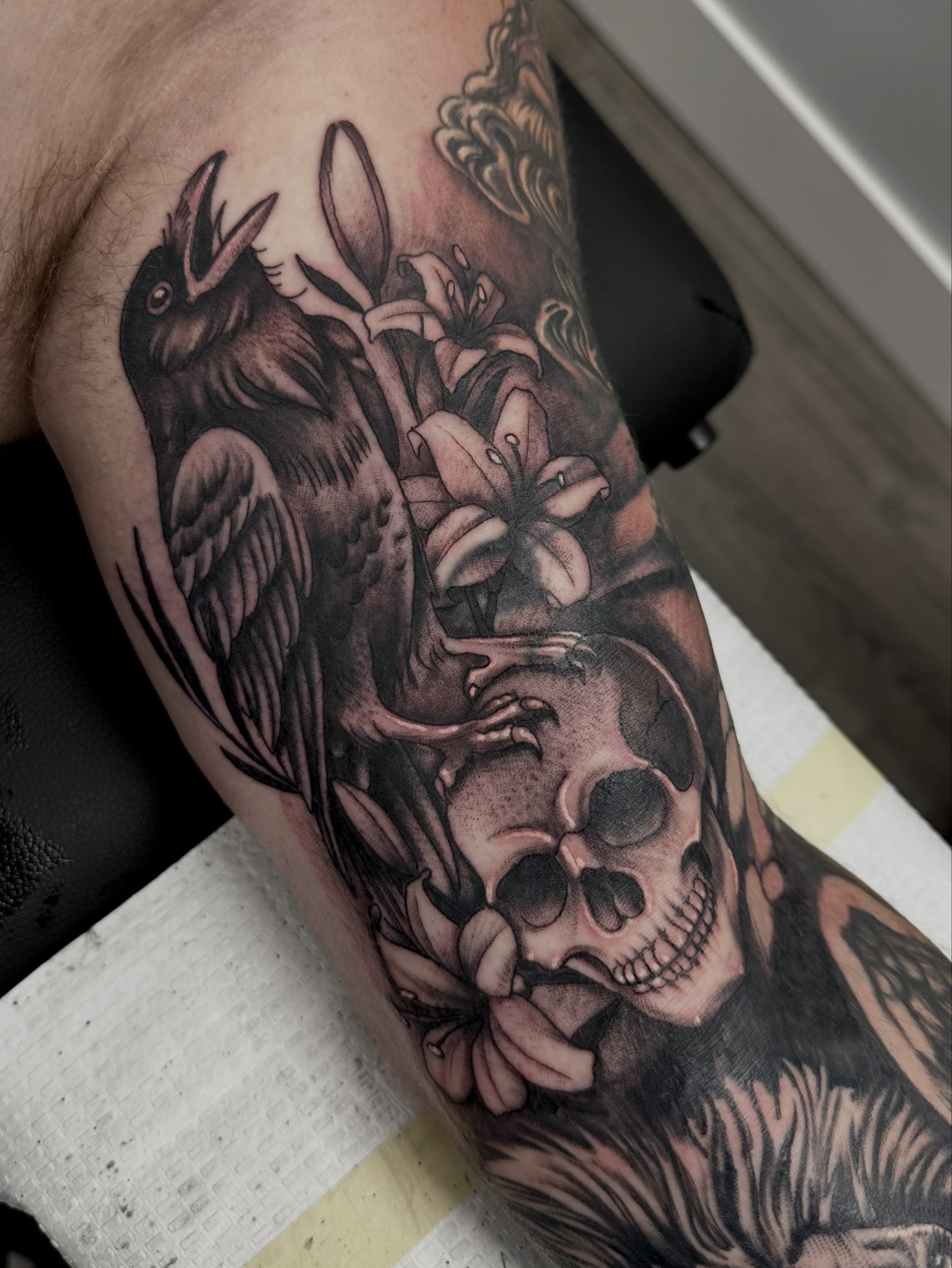 Crow, lilies, skull realism tattoo on the forearm by Vincent Merys