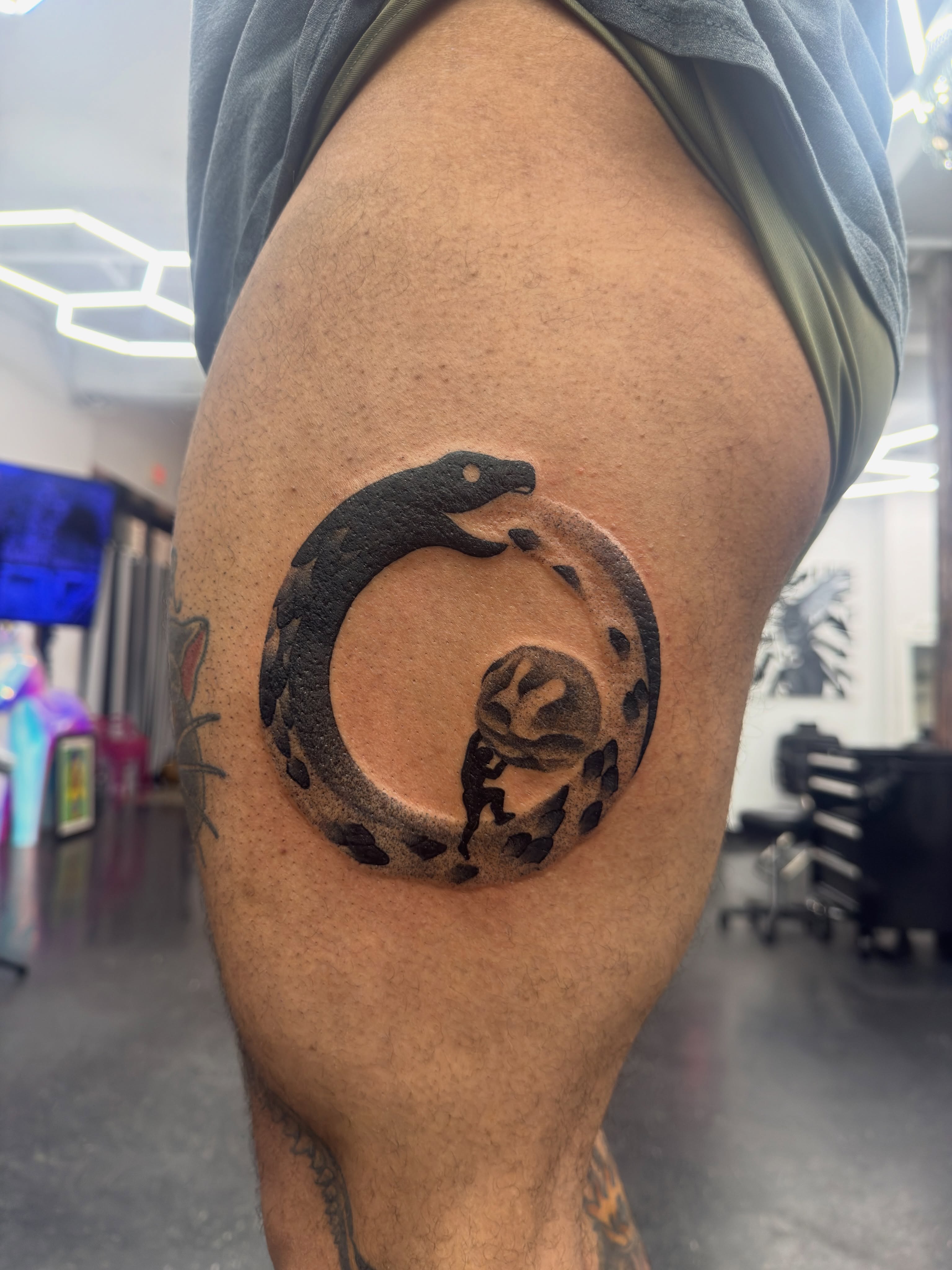 Snake and spiral black and grey tattoo on the thigh by Joshua Carter