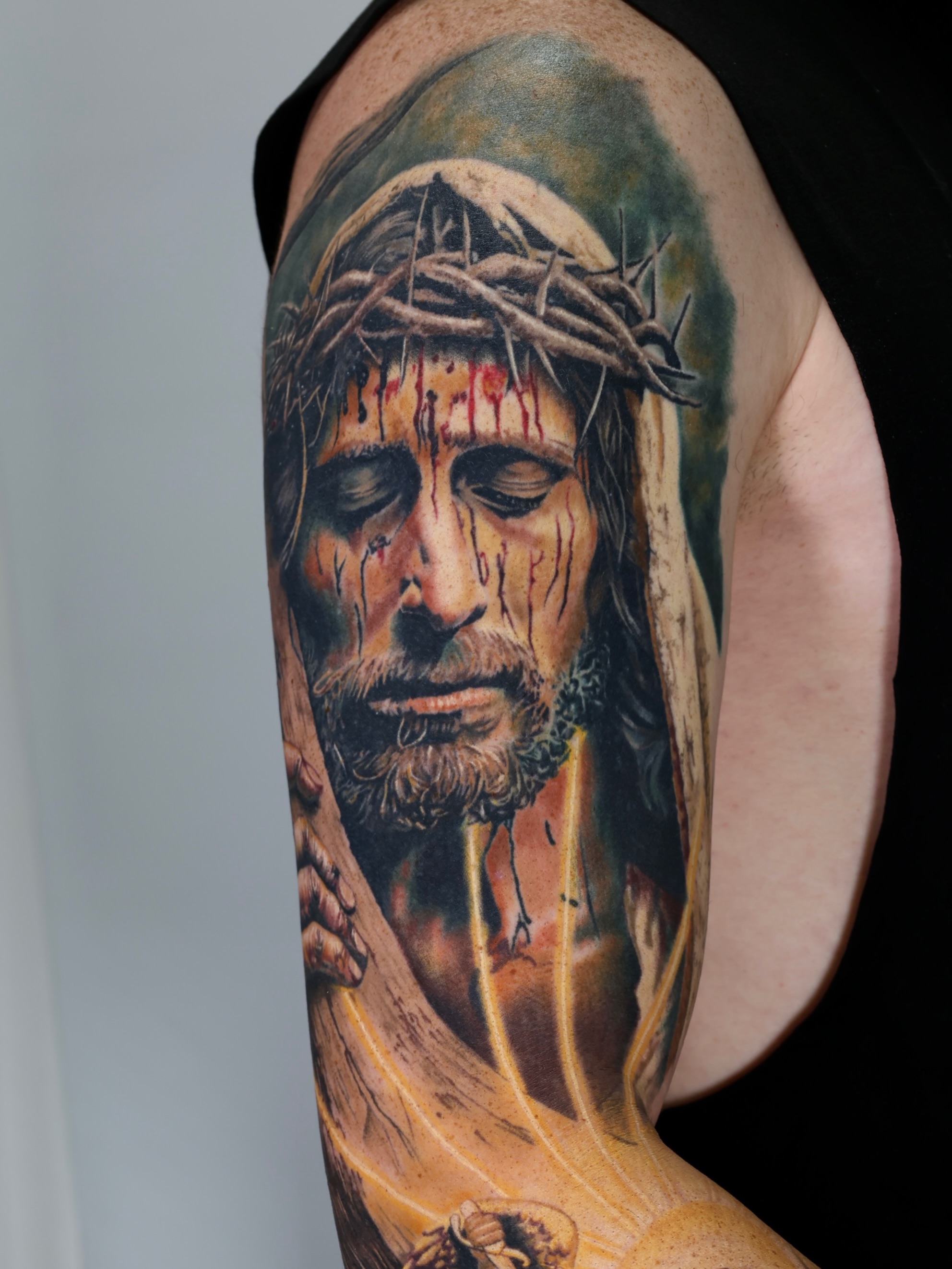 Jesus Christ realism tattoo on the upper arm by Leah Ross