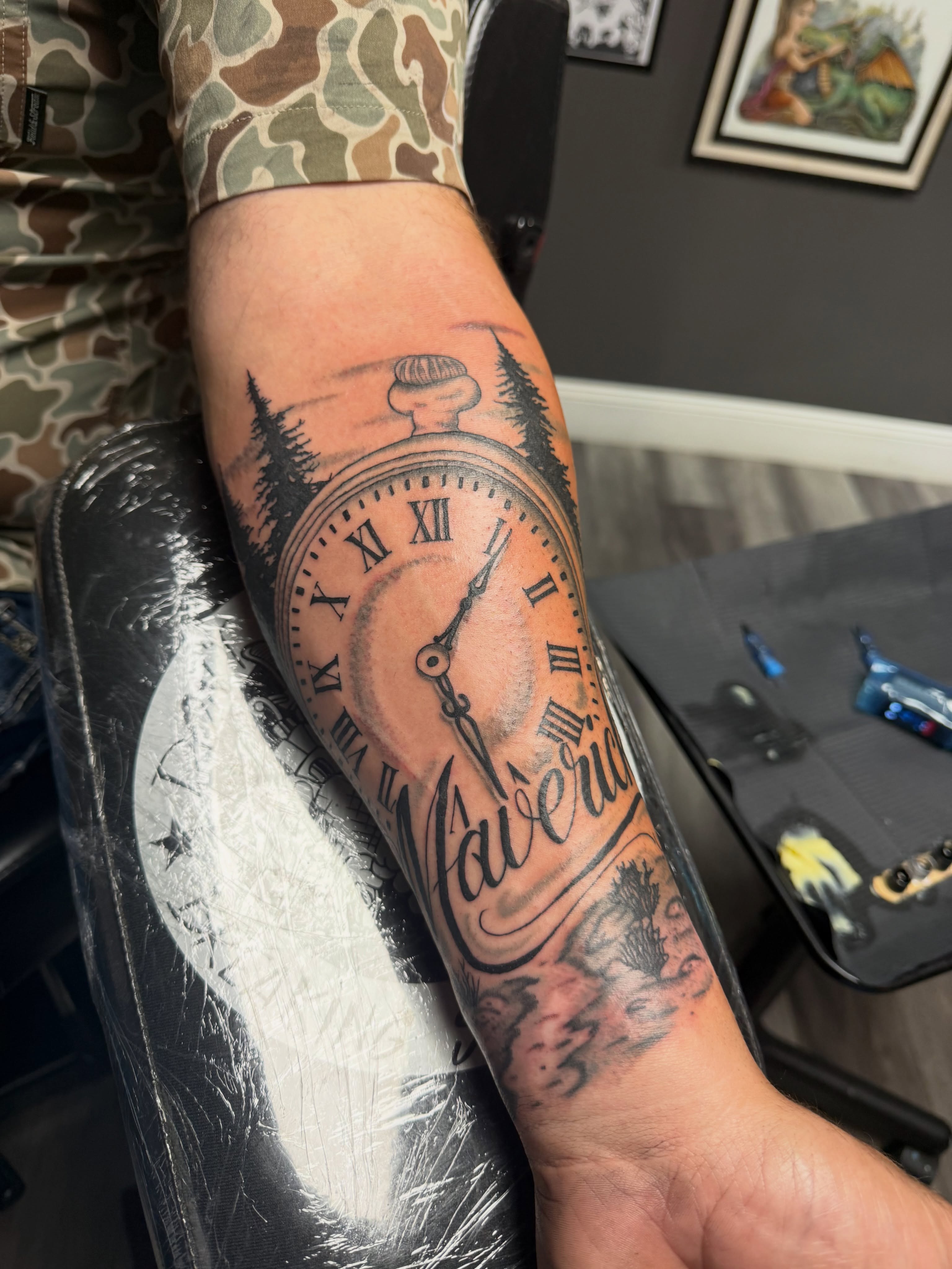 Clock and forest black and grey tattoo on the forearm by Justin George