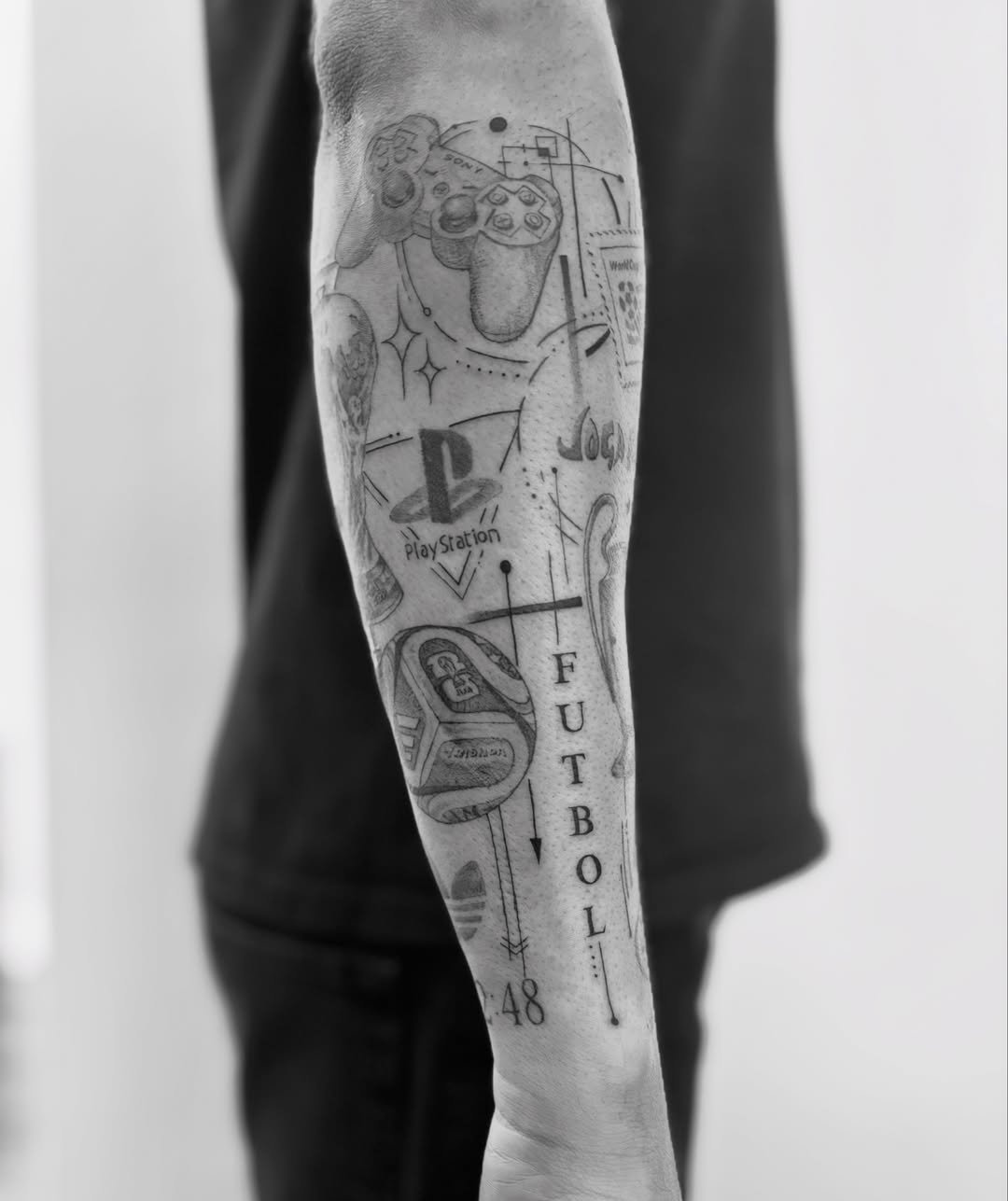 Video game controller and PlayStation logo black and grey tattoo on the forearm by @secretlinetattoo