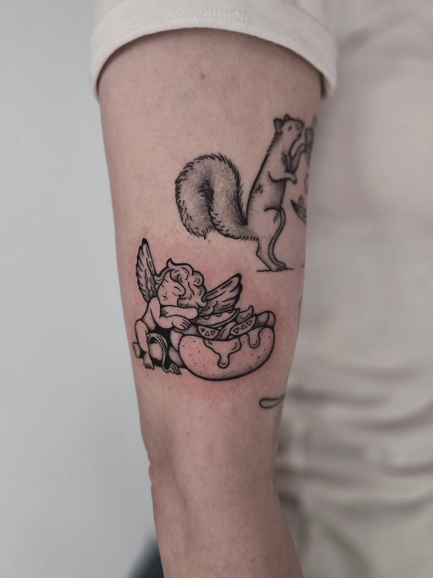 Angel and donut black and grey tattoo on the forearm by Kirstie Lew Tattoo