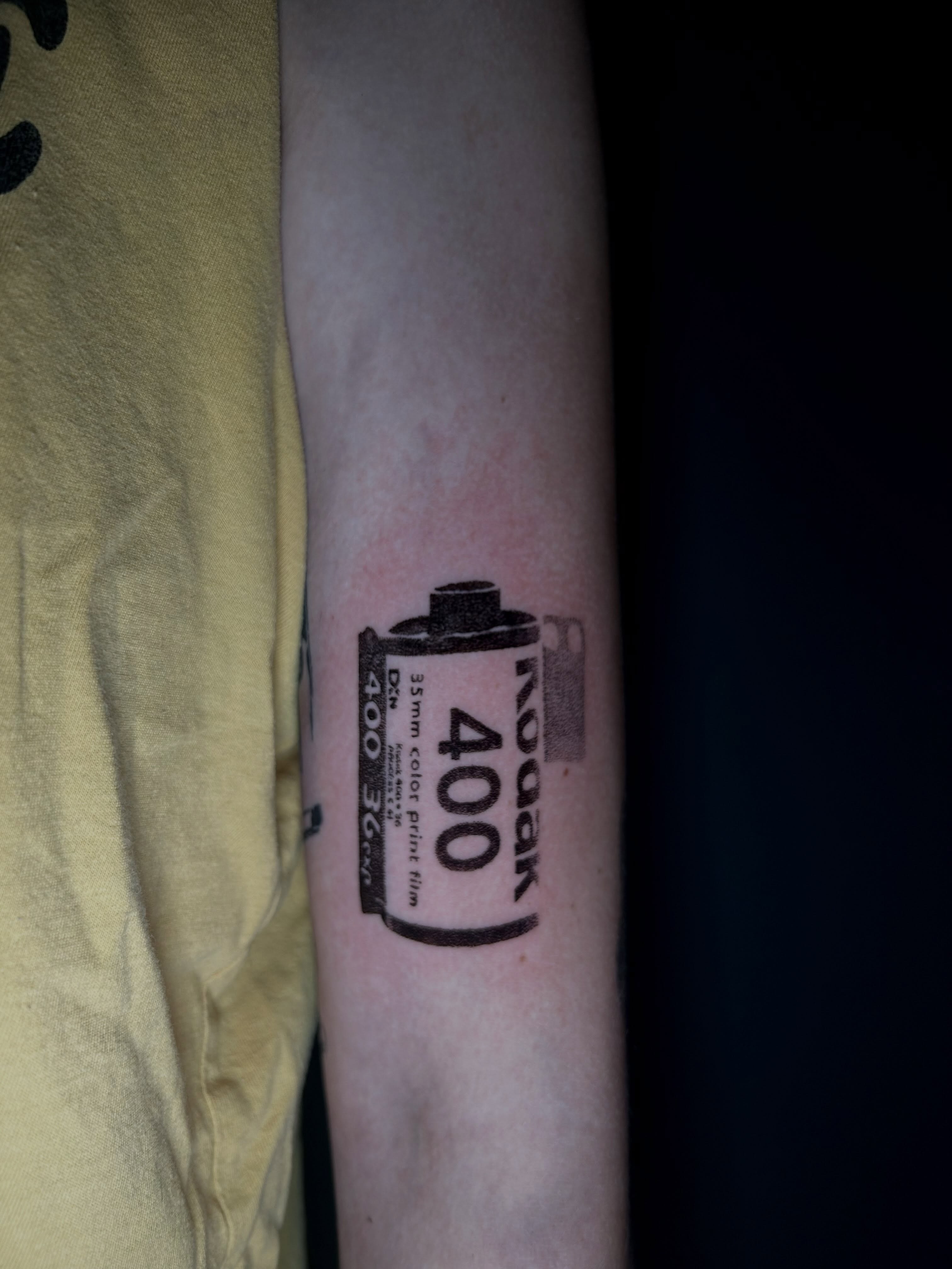 Film roll black and grey tattoo on the forearm by KB