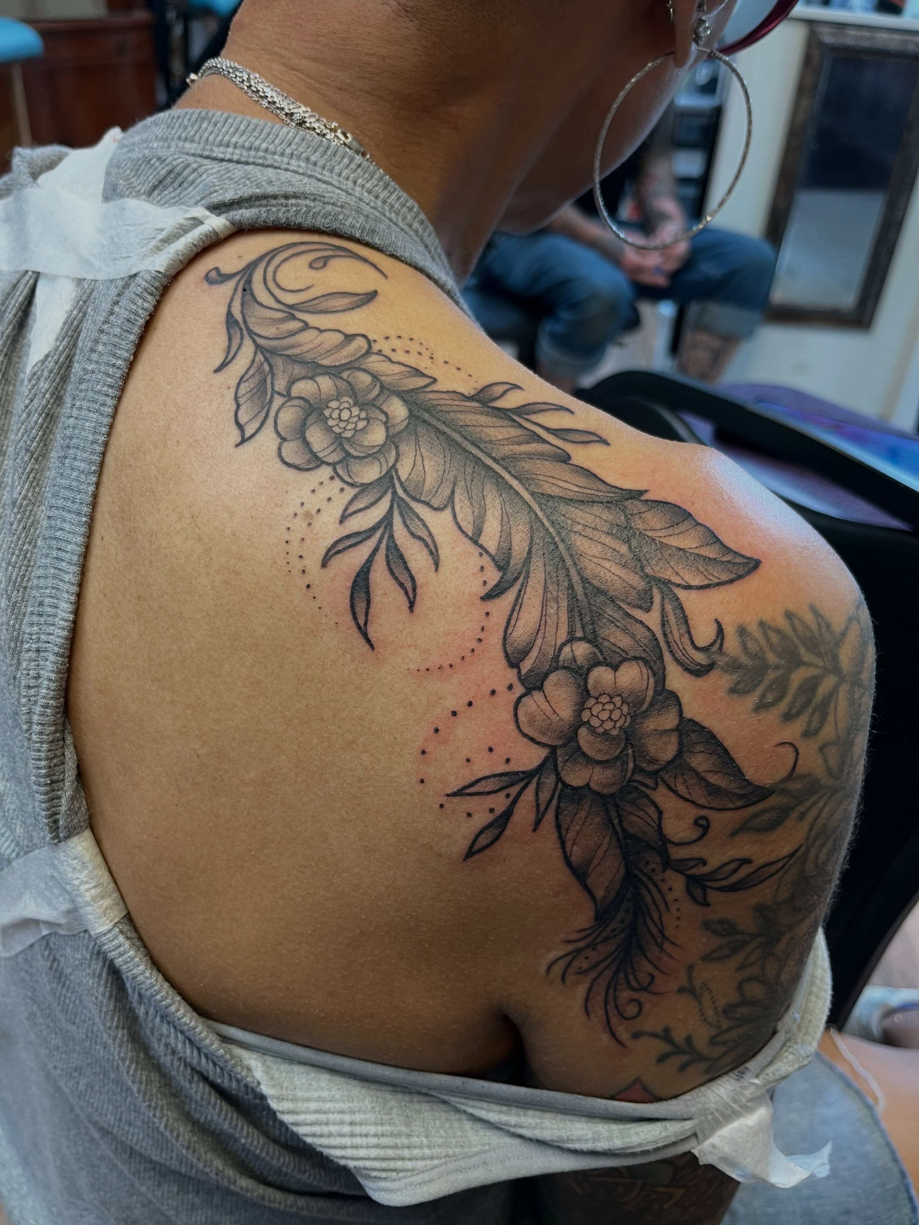 Feather and flowers black and grey tattoo on the shoulder by Danielle Lorandeau