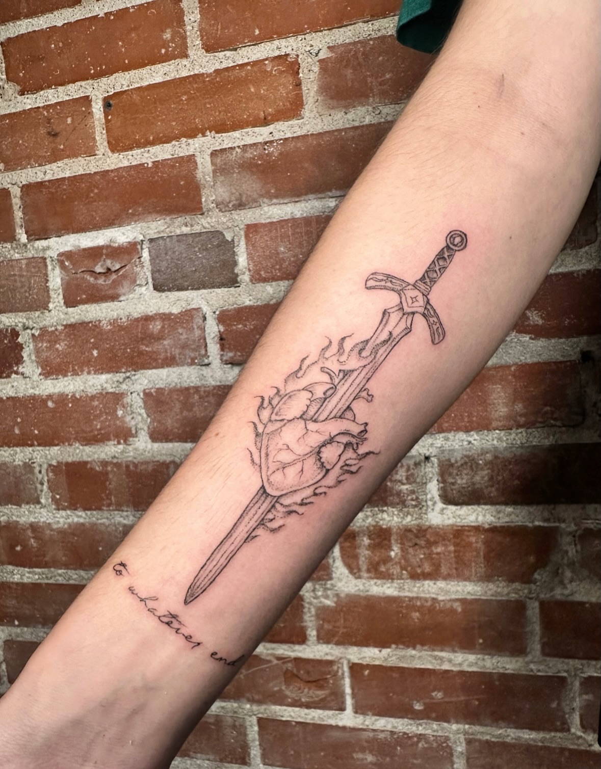 Sword and heart black and grey tattoo on the forearm by kenzie hunter