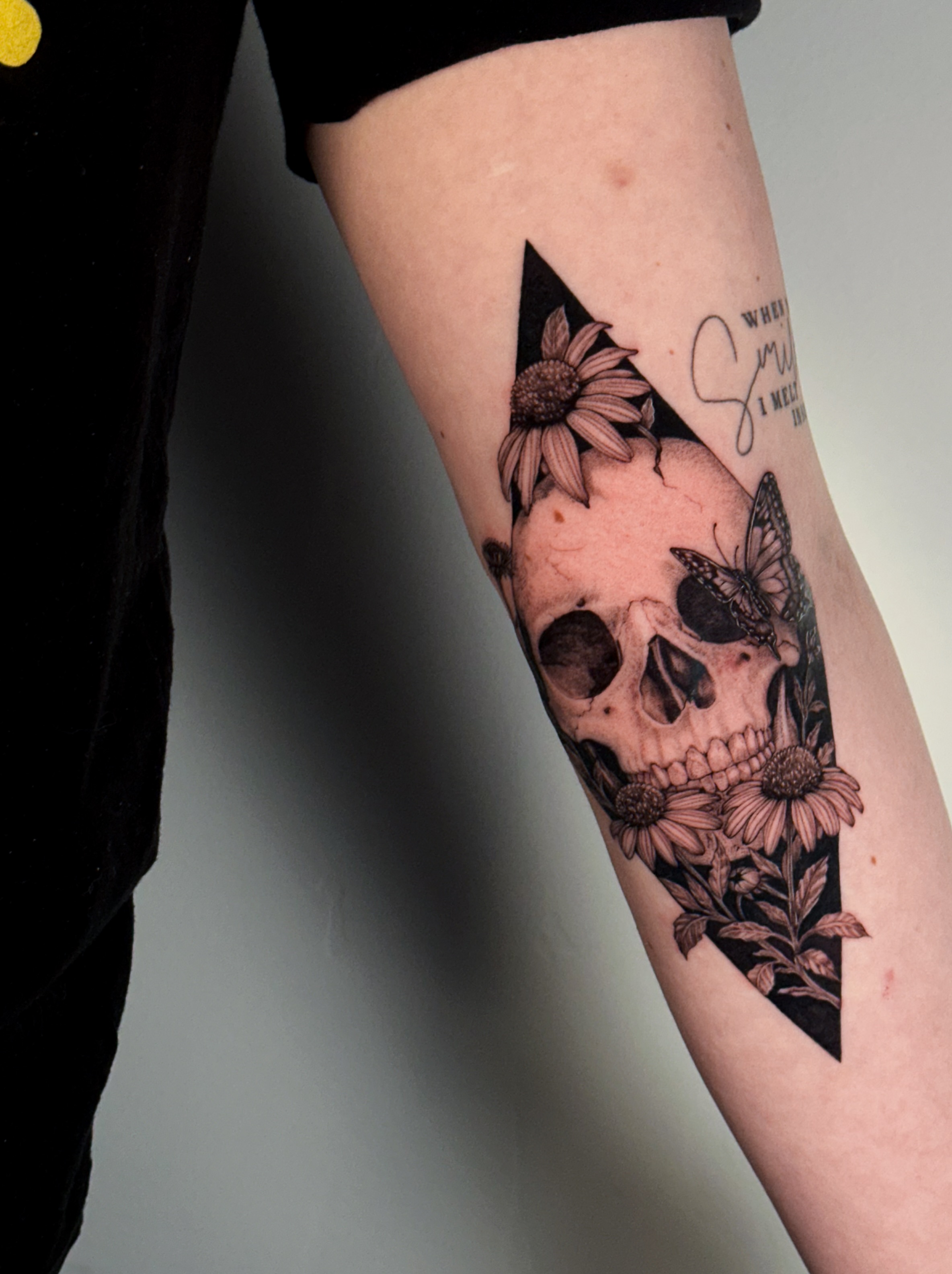 Skull and flowers realism tattoo on the forearm by Caroline + Utah Tattoo Artist