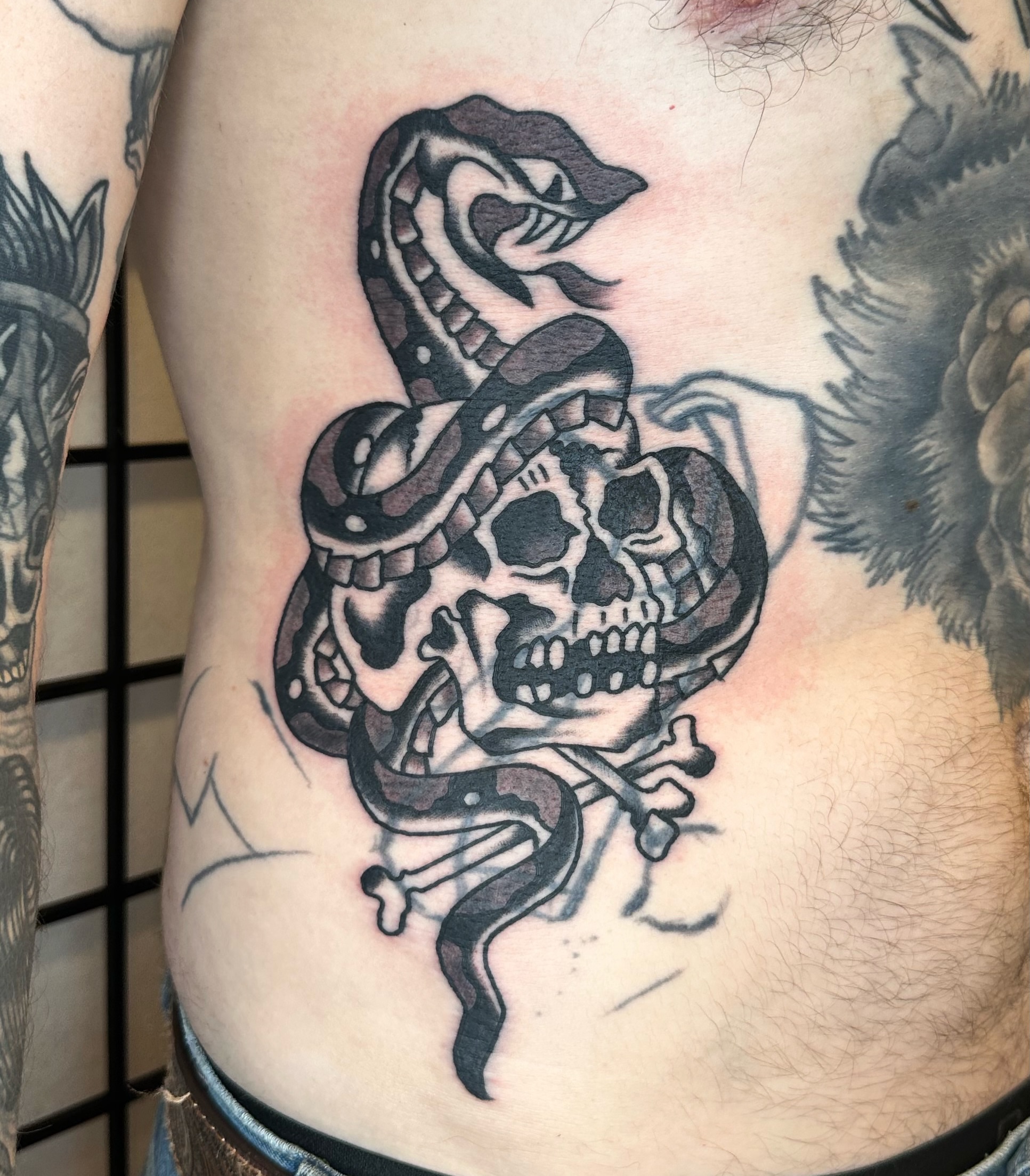 Snake and skull black and grey tattoo on the ribs by Brock Johnson