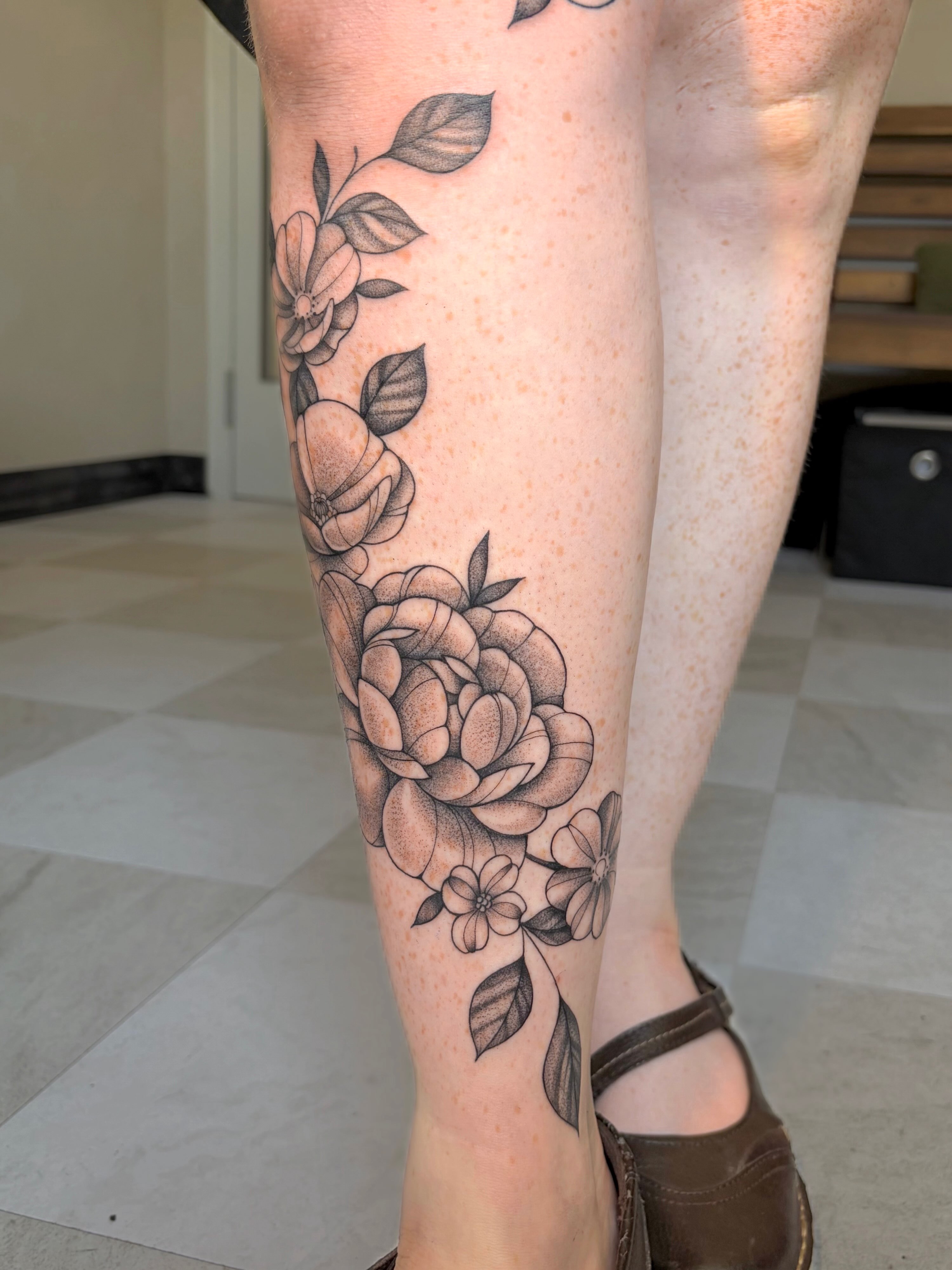 Floral arrangement realism tattoo on the calf by kuna ink