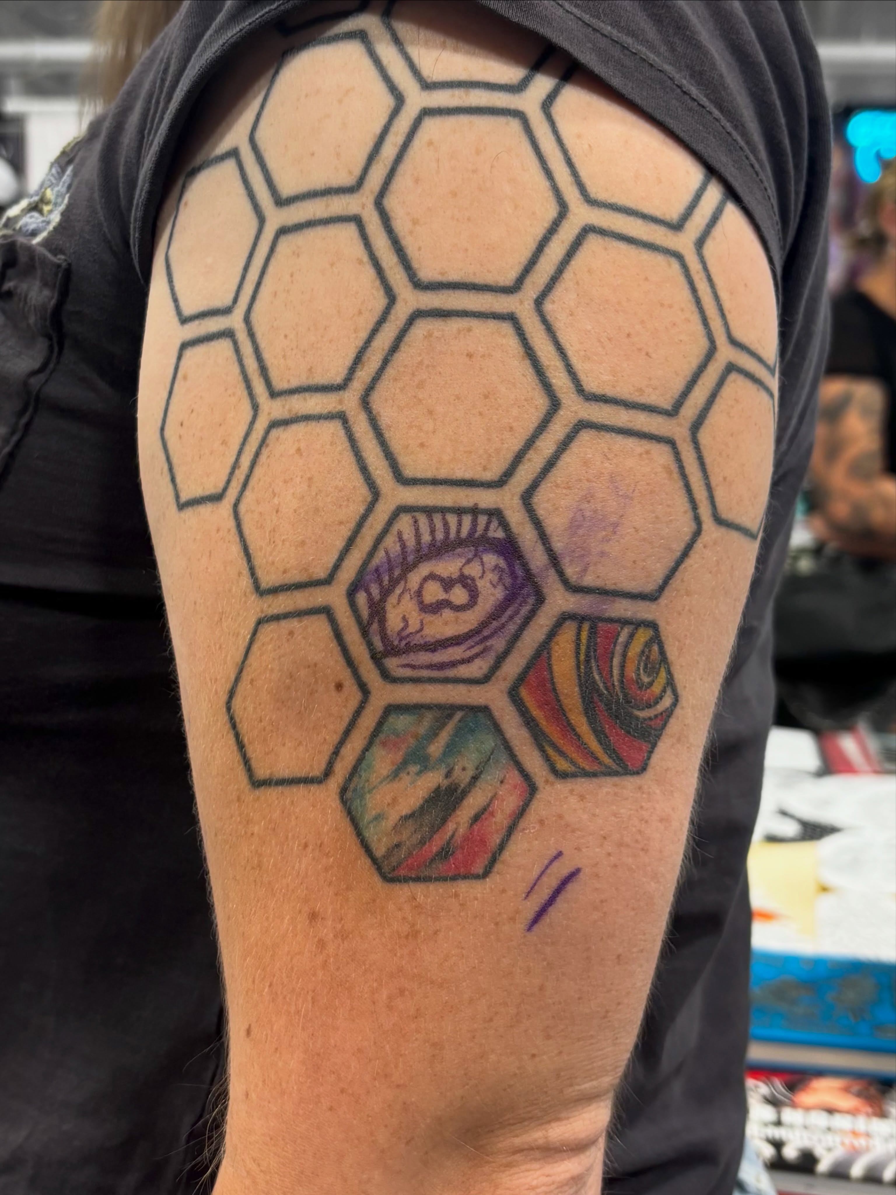 Hexagonal pattern with abstract shapes geometric tattoo on the upper arm by Nyah Ramirez
