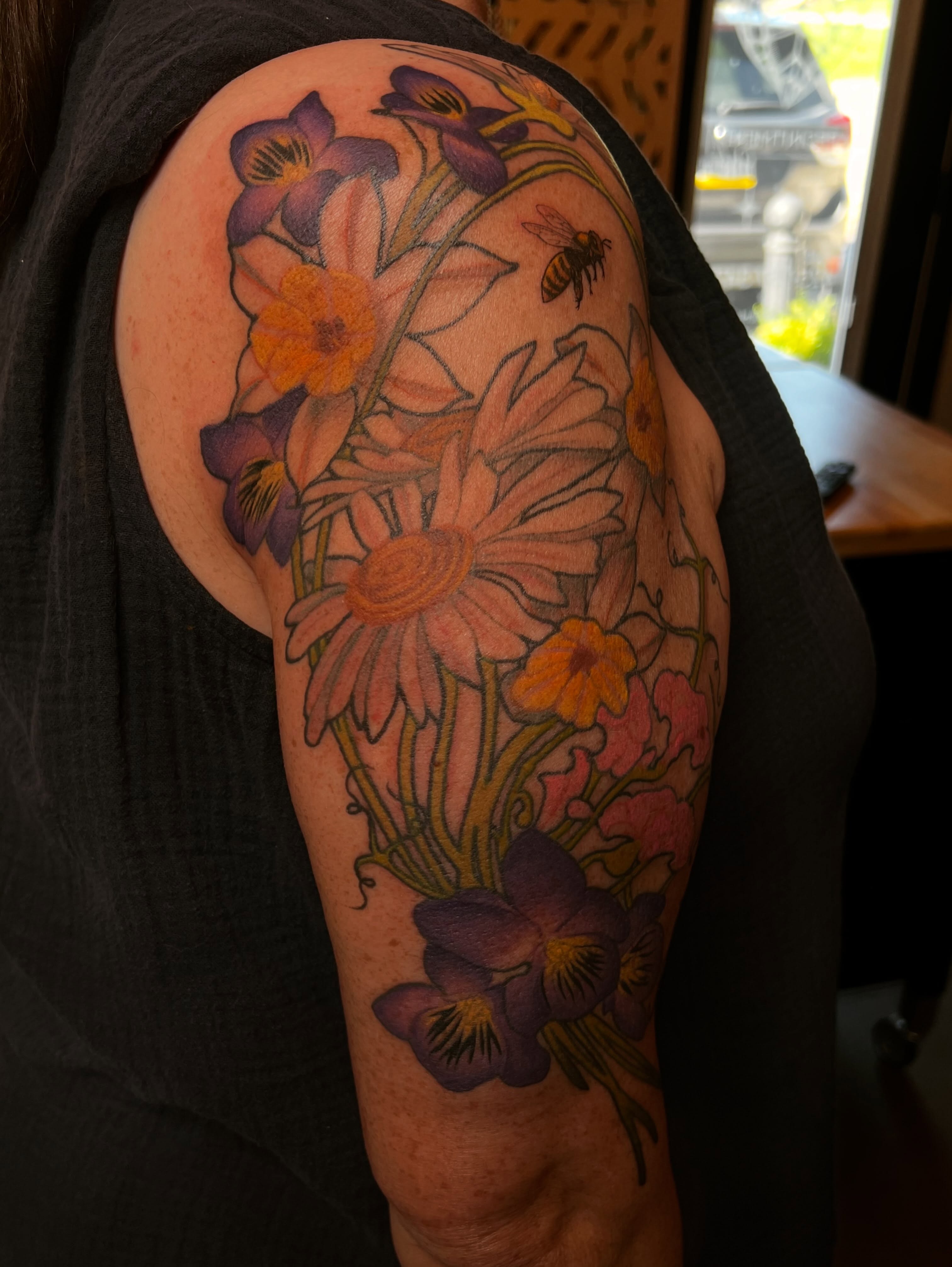Flowers and bee realism tattoo on the upper arm by Amanda Leitch