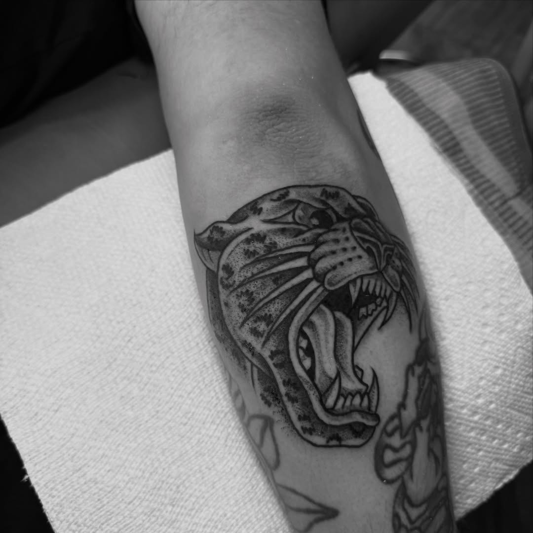 Roaring panther black and grey tattoo on the forearm by Ramón Silva