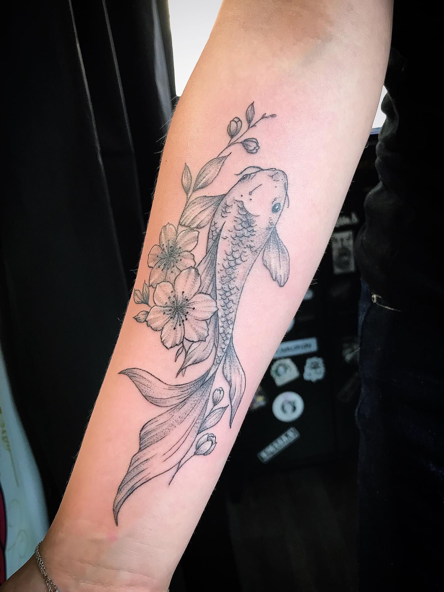 Koi fish and cherry blossoms black and grey tattoo on the forearm by Moss Quito Tattoo