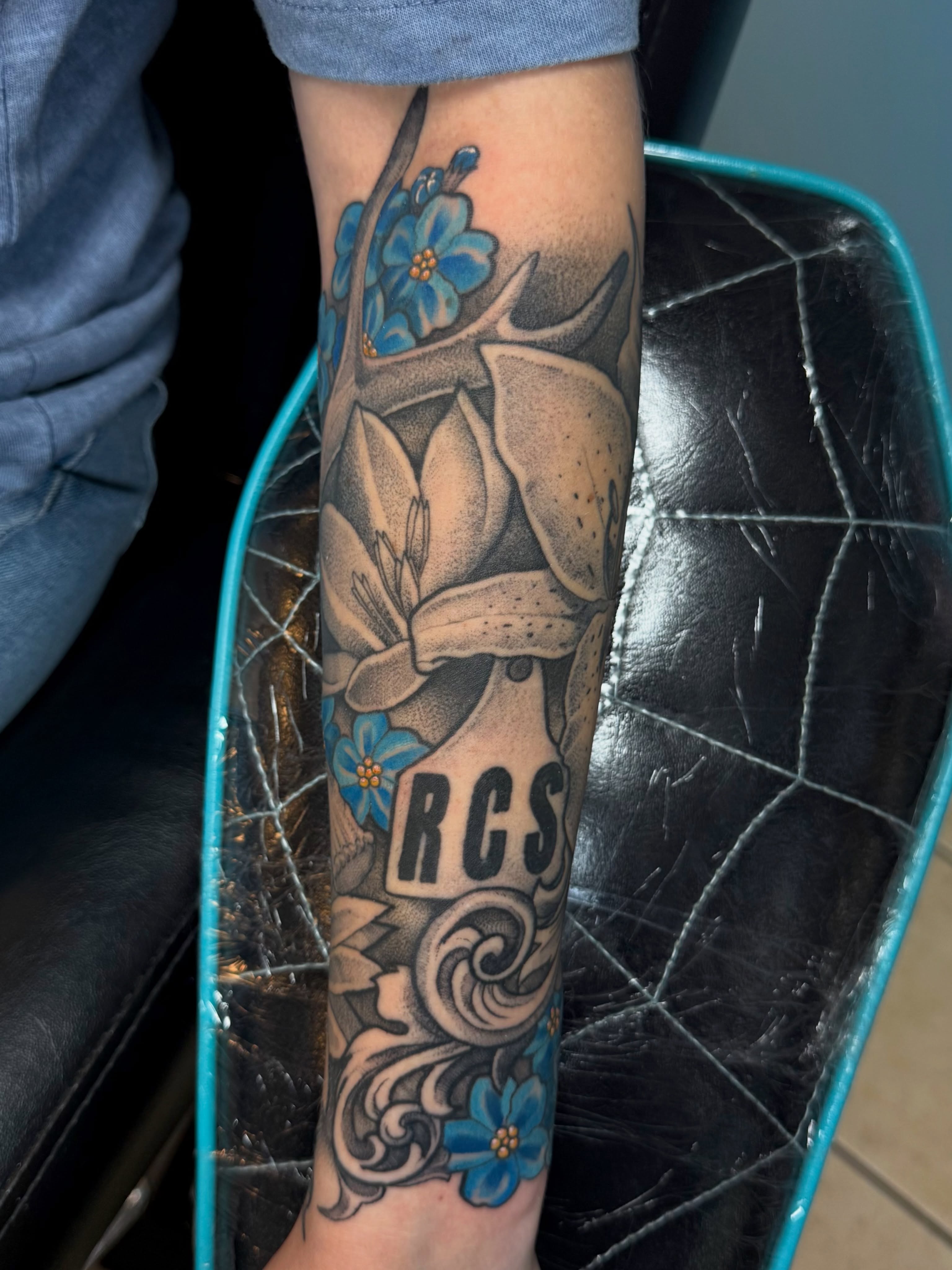Lily and forget-me-nots American traditional tattoo on the forearm by Rebecca Preble