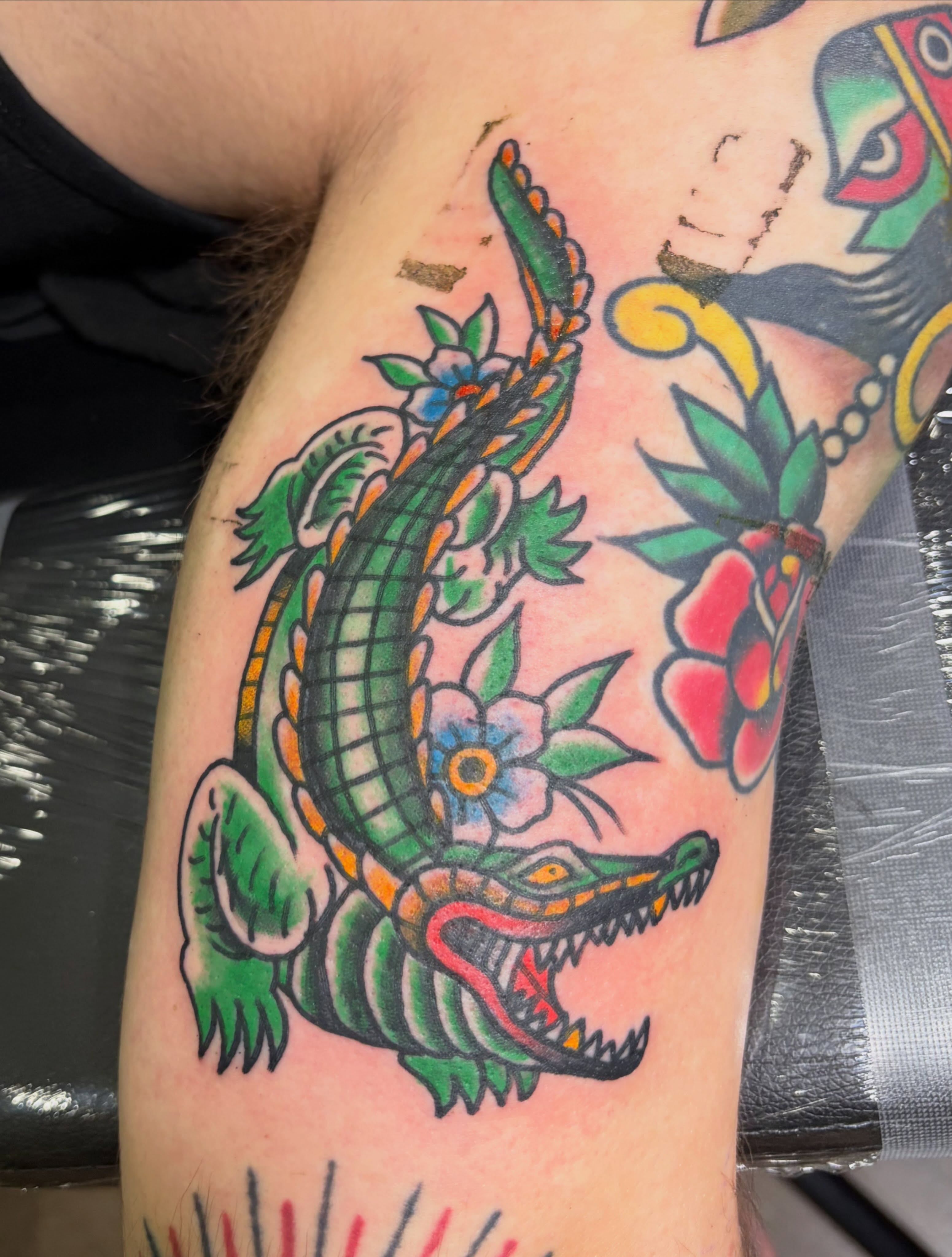 Crocodile and flowers American traditional tattoo on the forearm by Scrap Iron Tattoos