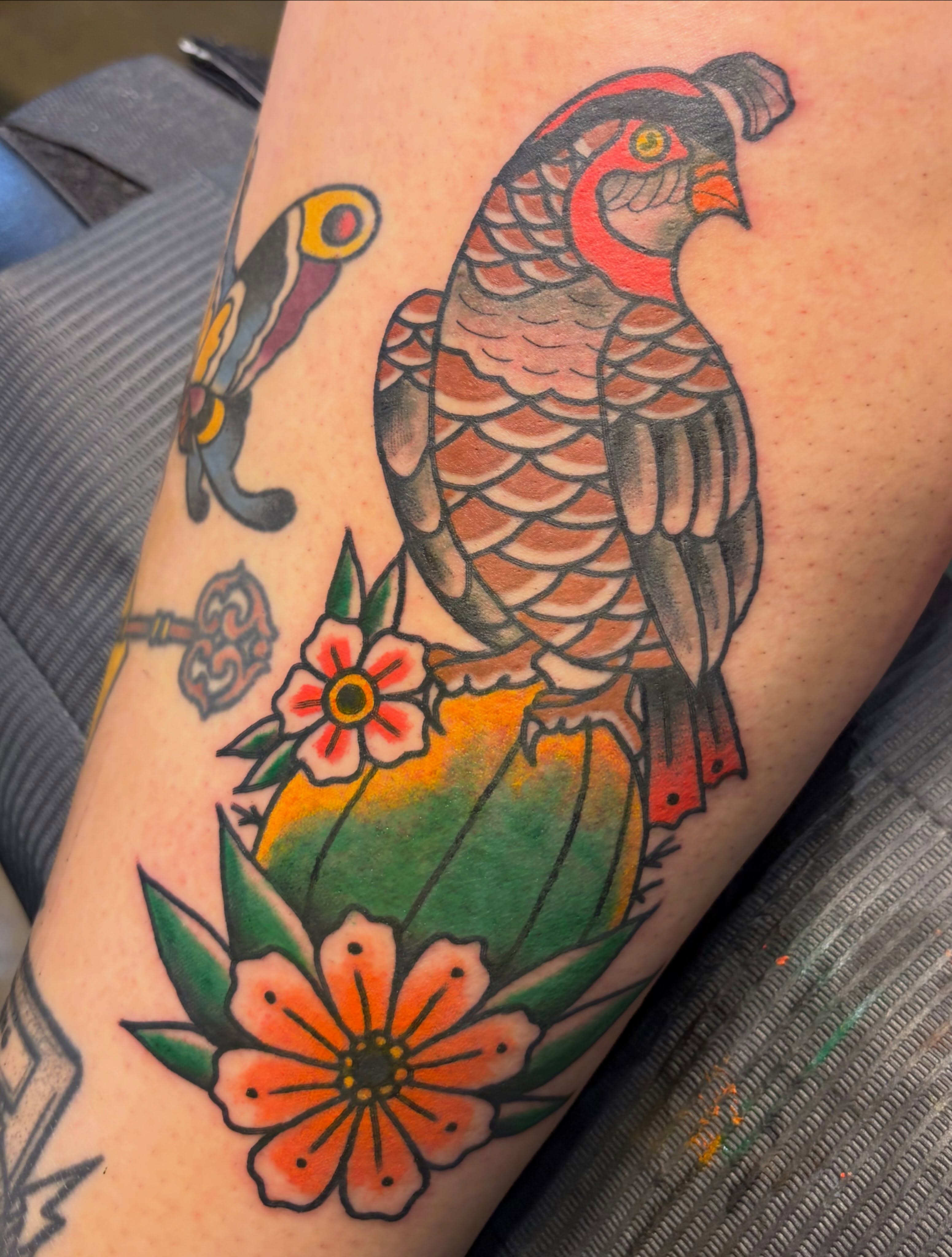 Parrot and flowers American traditional tattoo on the forearm by Scrap Iron Tattoos