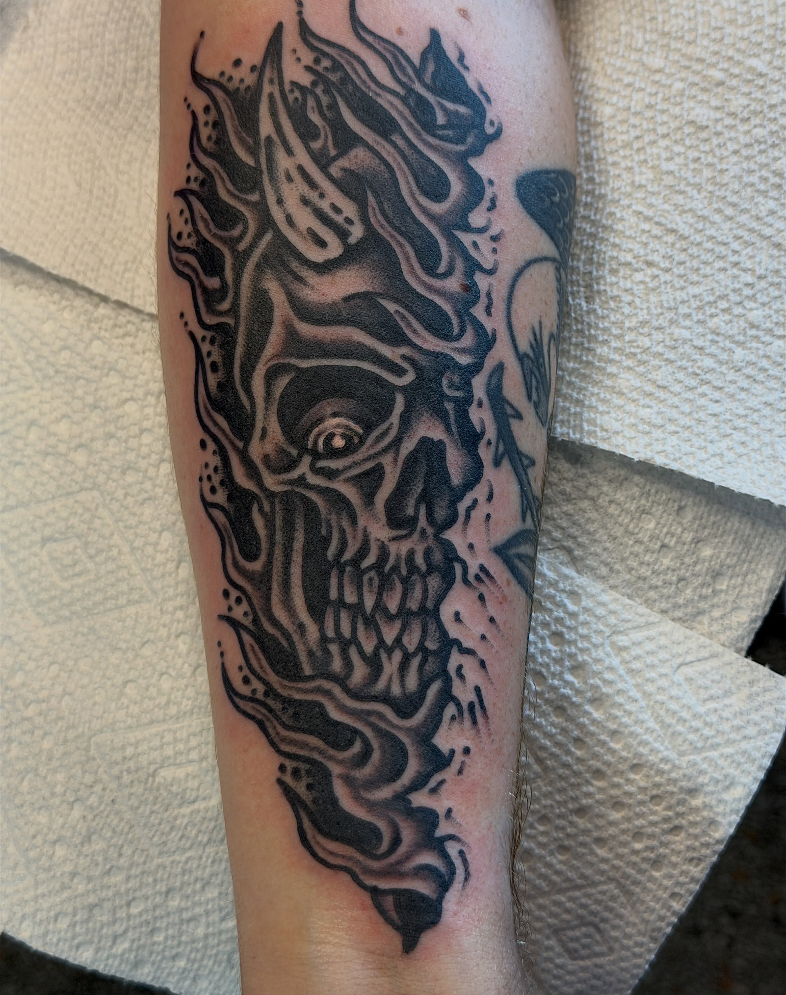 Flaming skull black and grey tattoo on the forearm by Joshua Speight