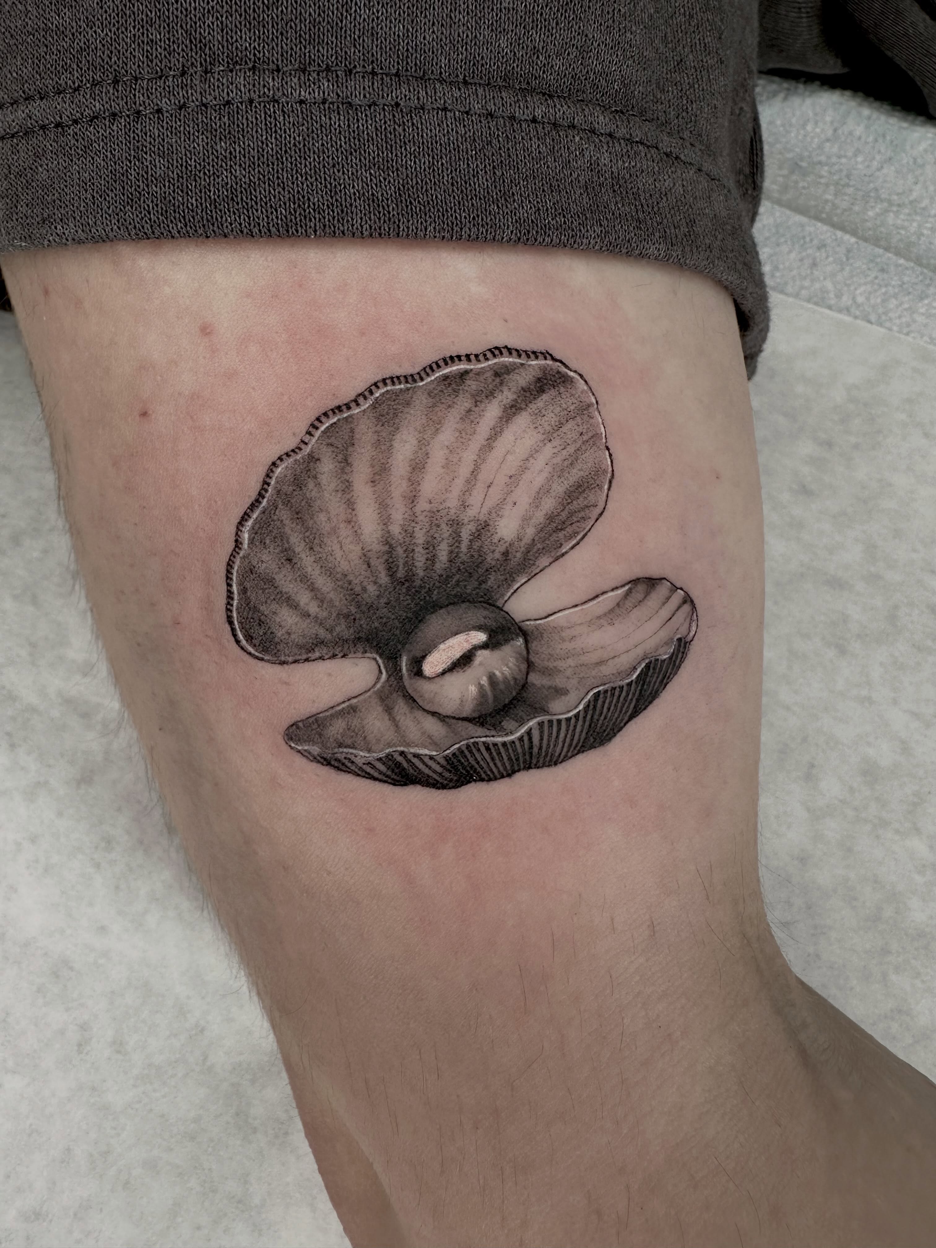 Shell black and grey tattoo on the thigh by Em Krieg