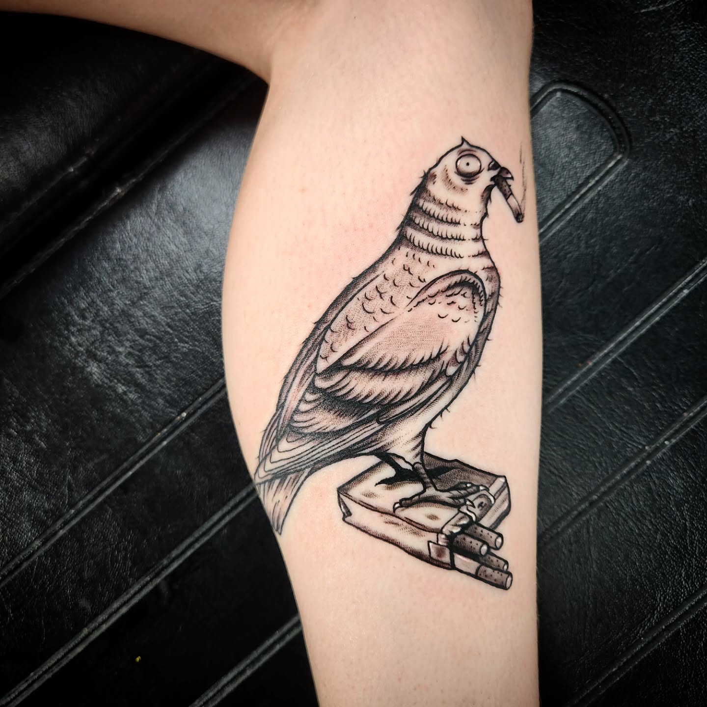 Bird perched on cigarettes black and grey tattoo on the forearm by Eric Richards