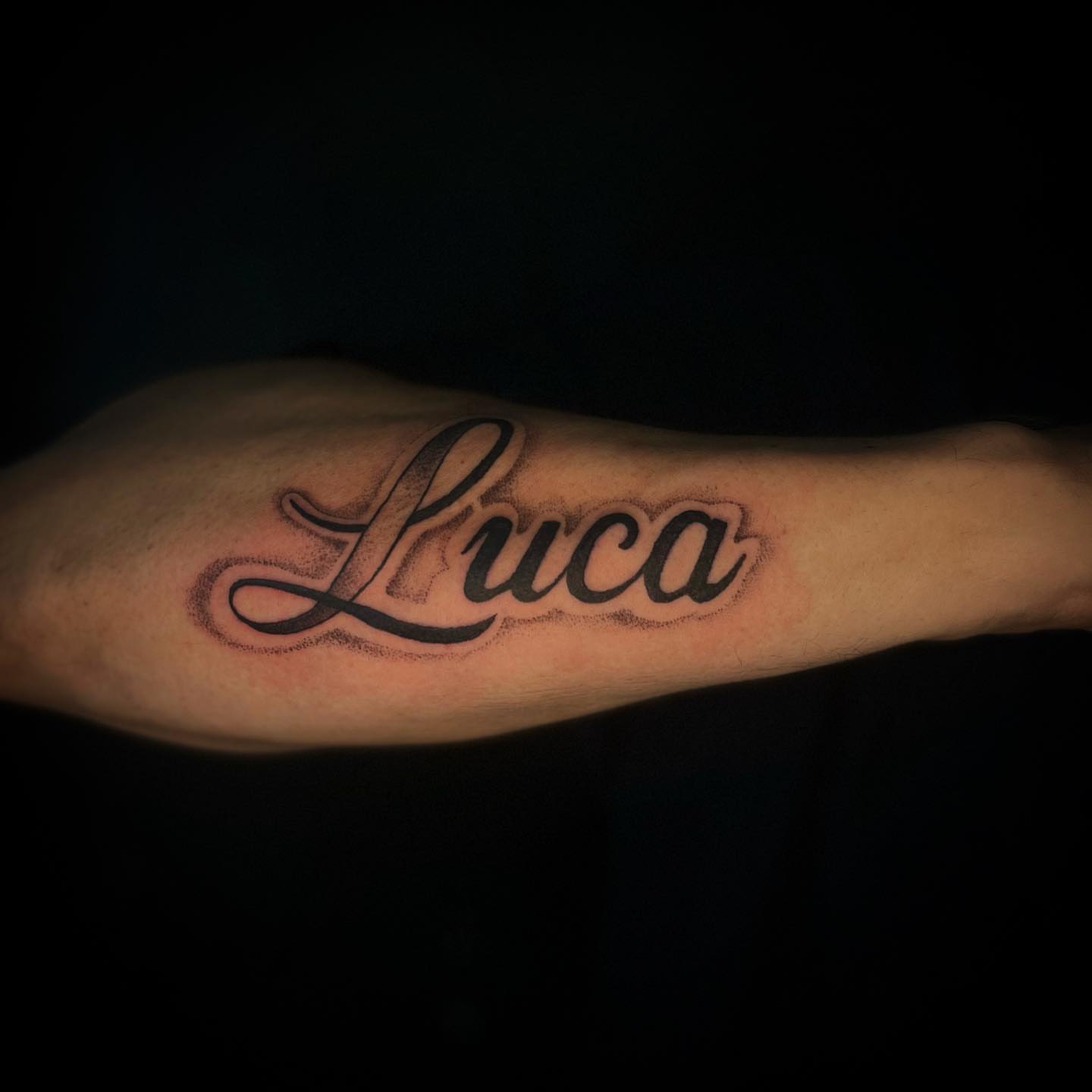 Luca lettering script tattoo on the forearm by Angie Milano